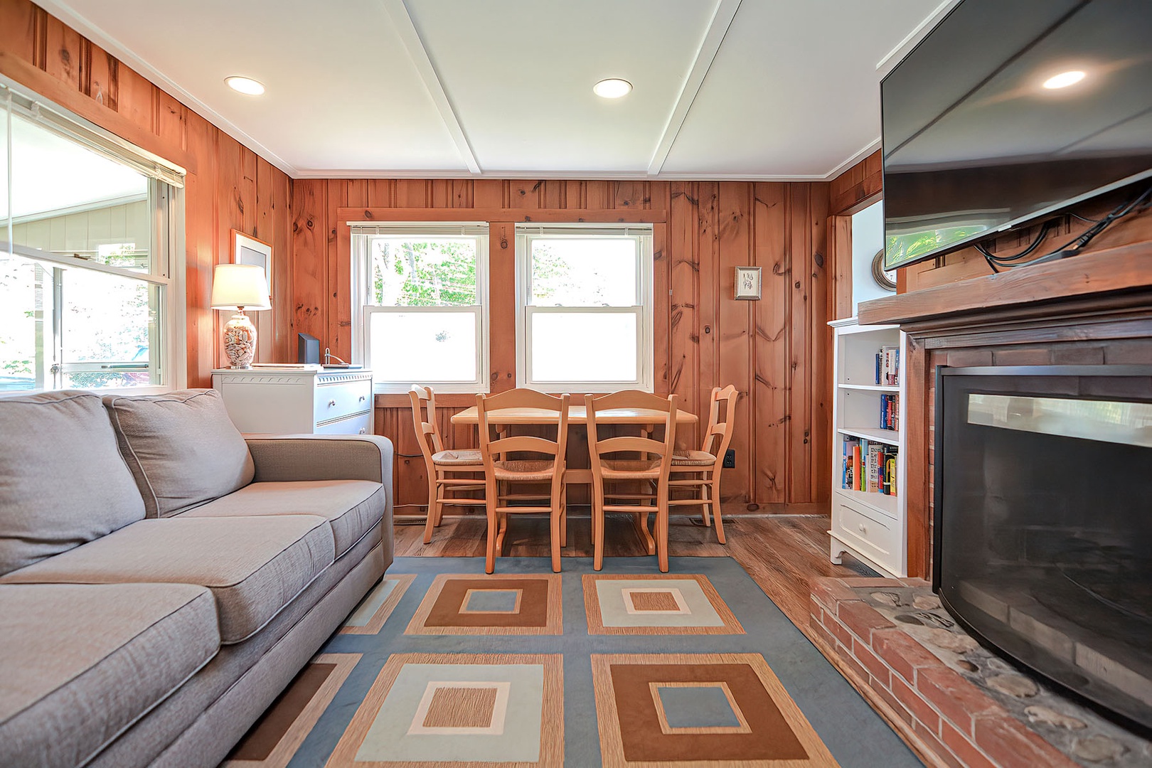 The living room has a large screen TV, fireplace, and dining area.