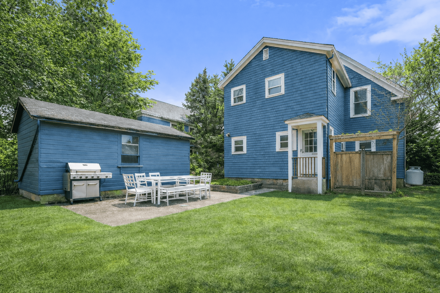 Spacious backyard and outdoor sitting area surrounded by lush greenery.