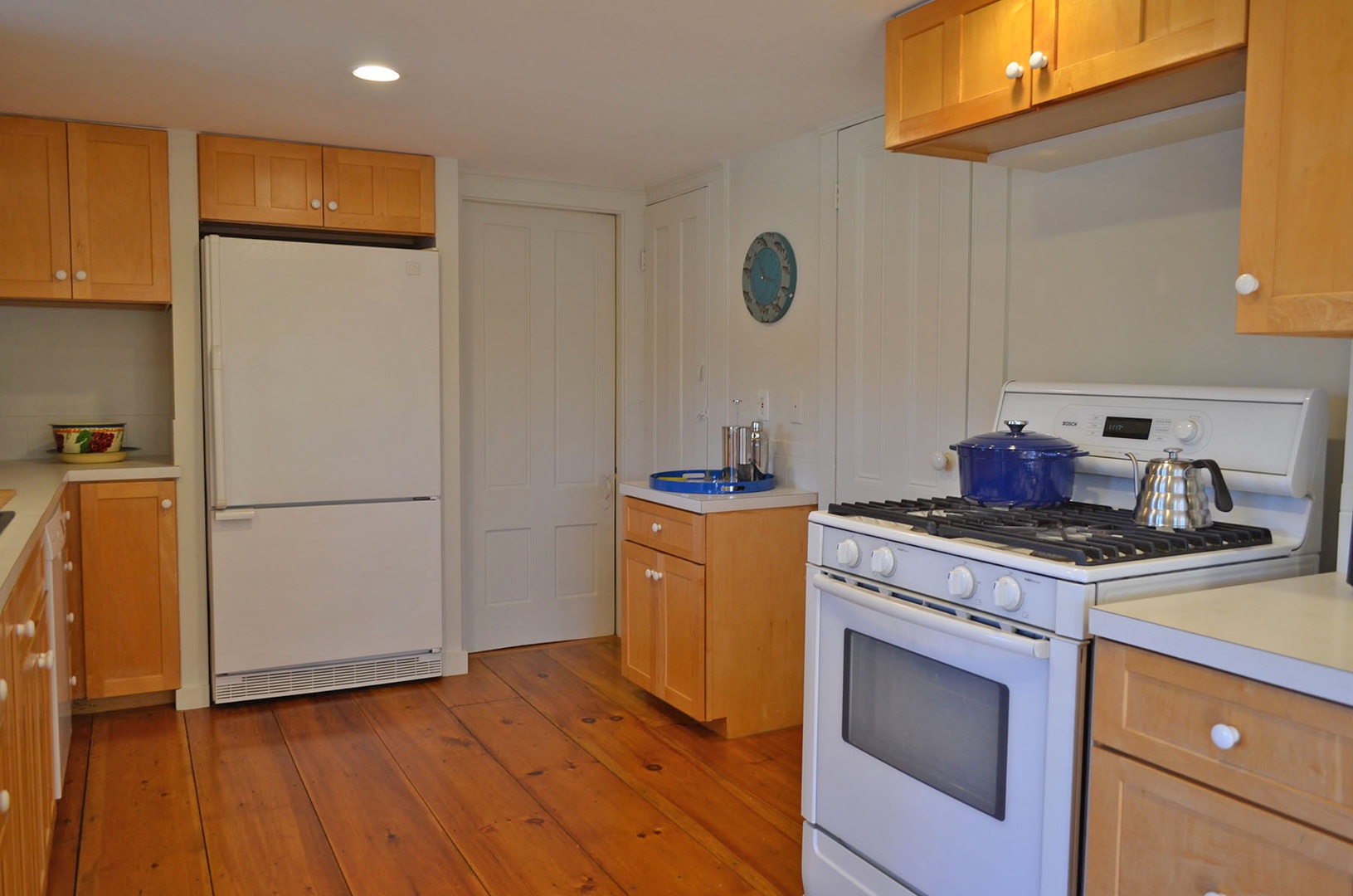 A well-applianced kitchen includes a gas stove and refrigerator.
