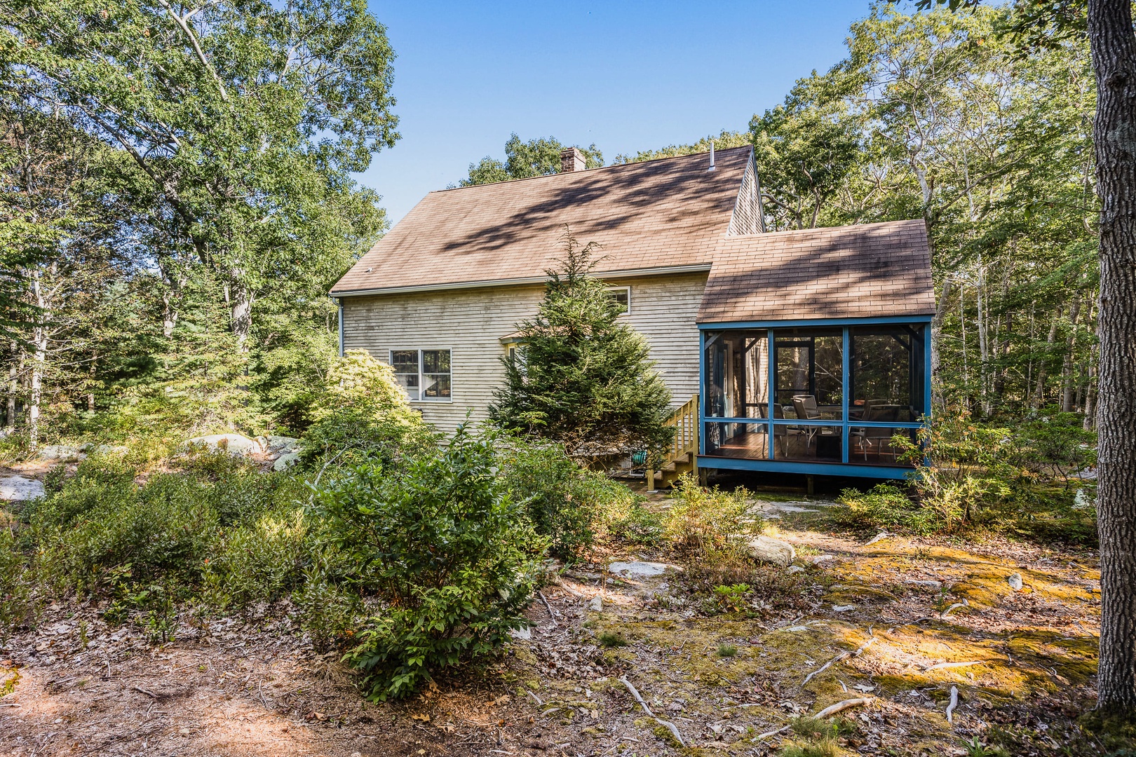 The screened porch, covered with trees all around.