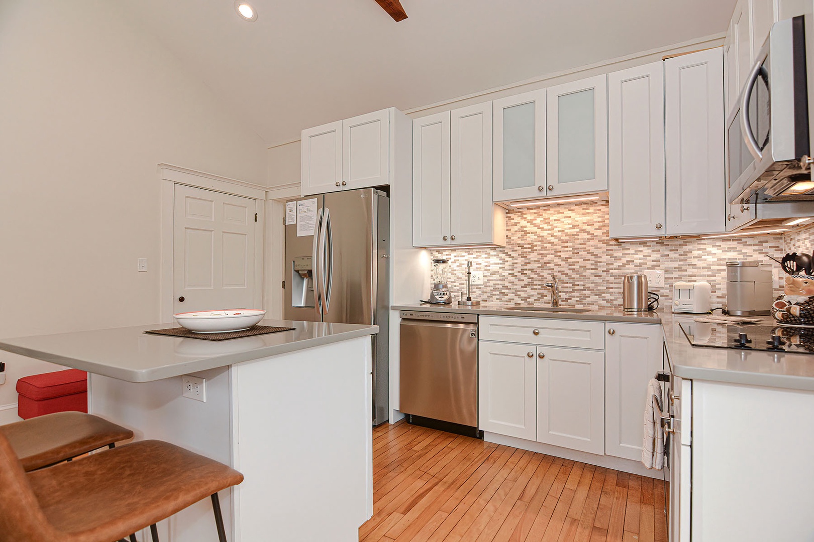 A well-equipped kitchen with stainless steel appliances including an induction stove top, and plenty of cabinet space. The center island serves as a breakfast bar/eat-in kitchen accommodating up to 2 people comfortably.