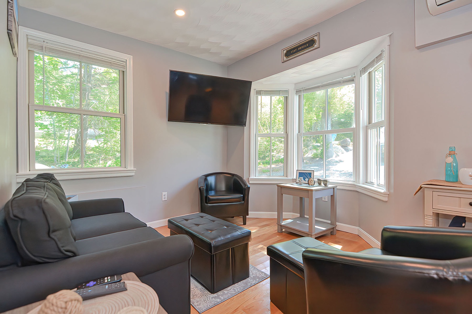 The cozy living room has a bay window and a flatscreen TV.