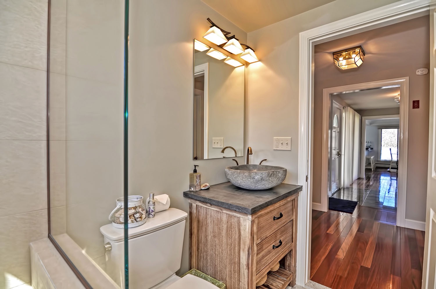 Full bath with elegant glass and tile shower, off the main hall.