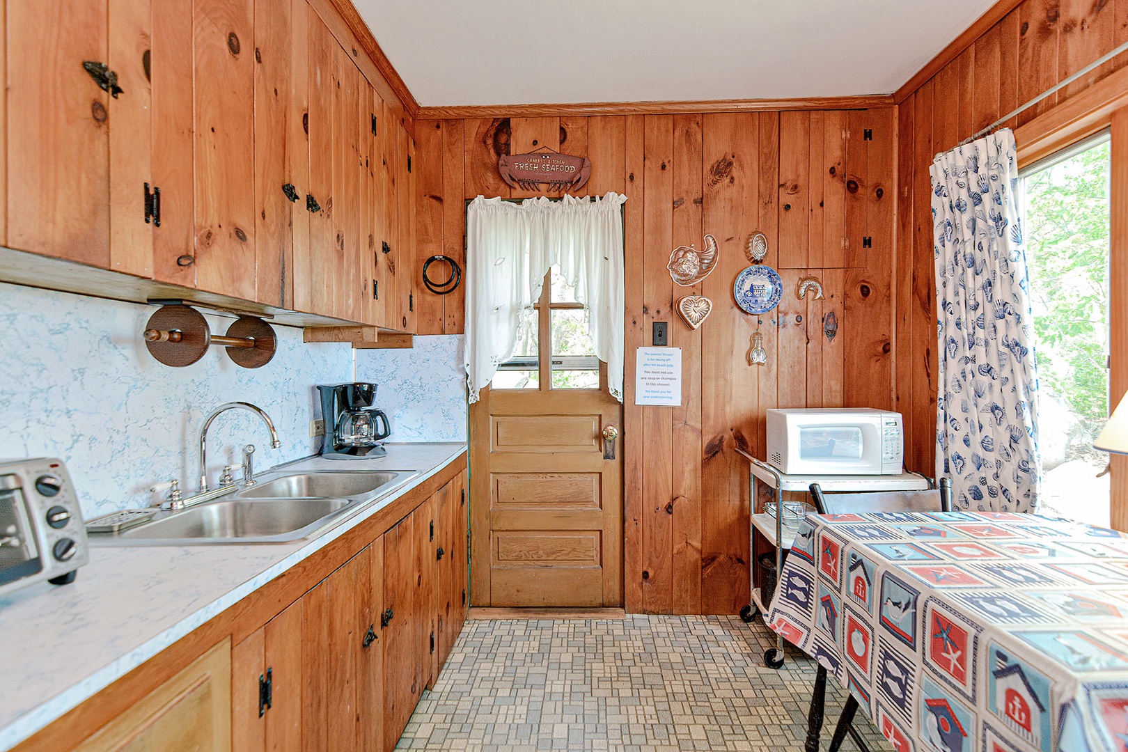 The simple cottage kitchen has pine cabinetry and paneling.