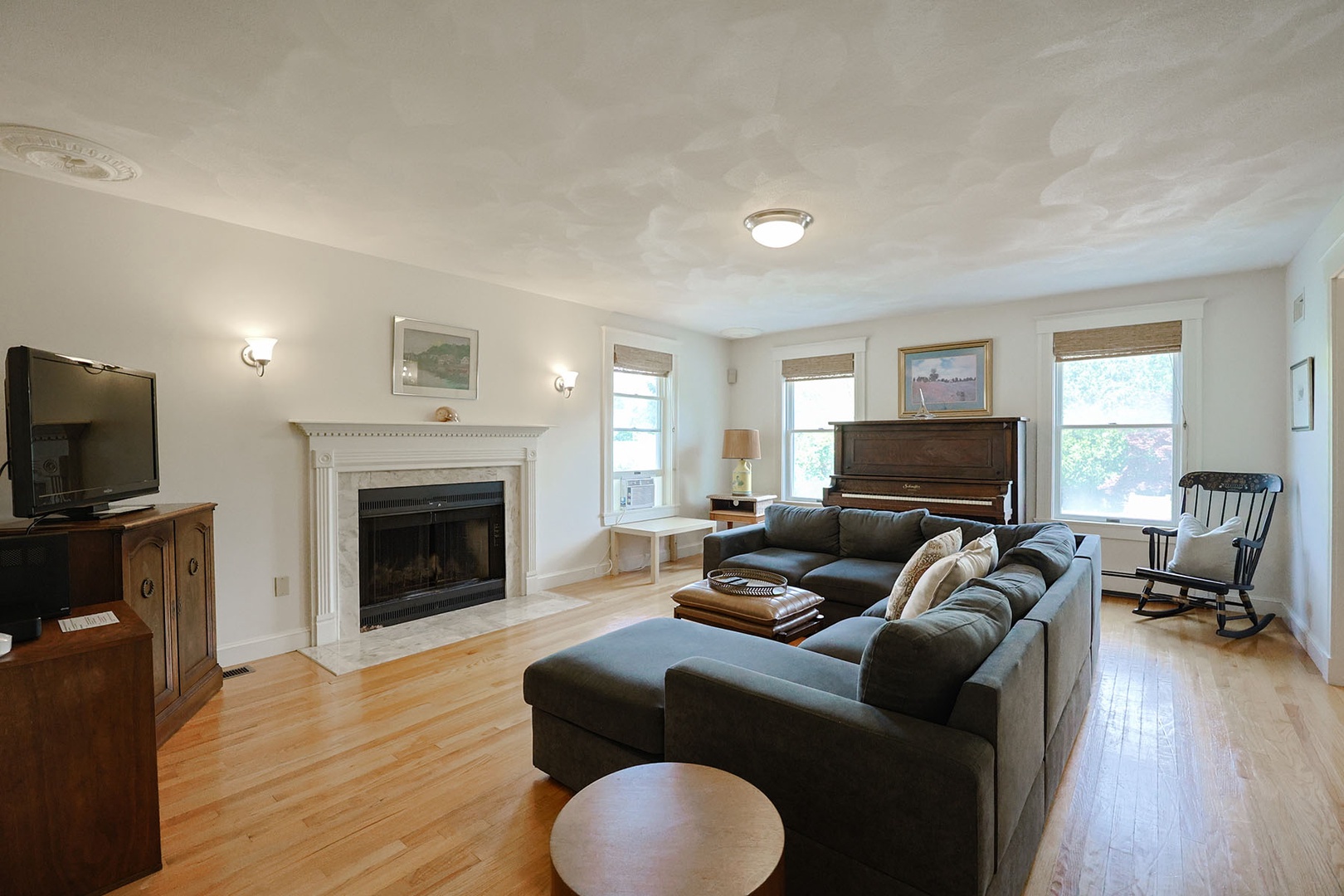 Living Room 1:  Large sectional couch, flat-screen TV, piano, and fireplace.