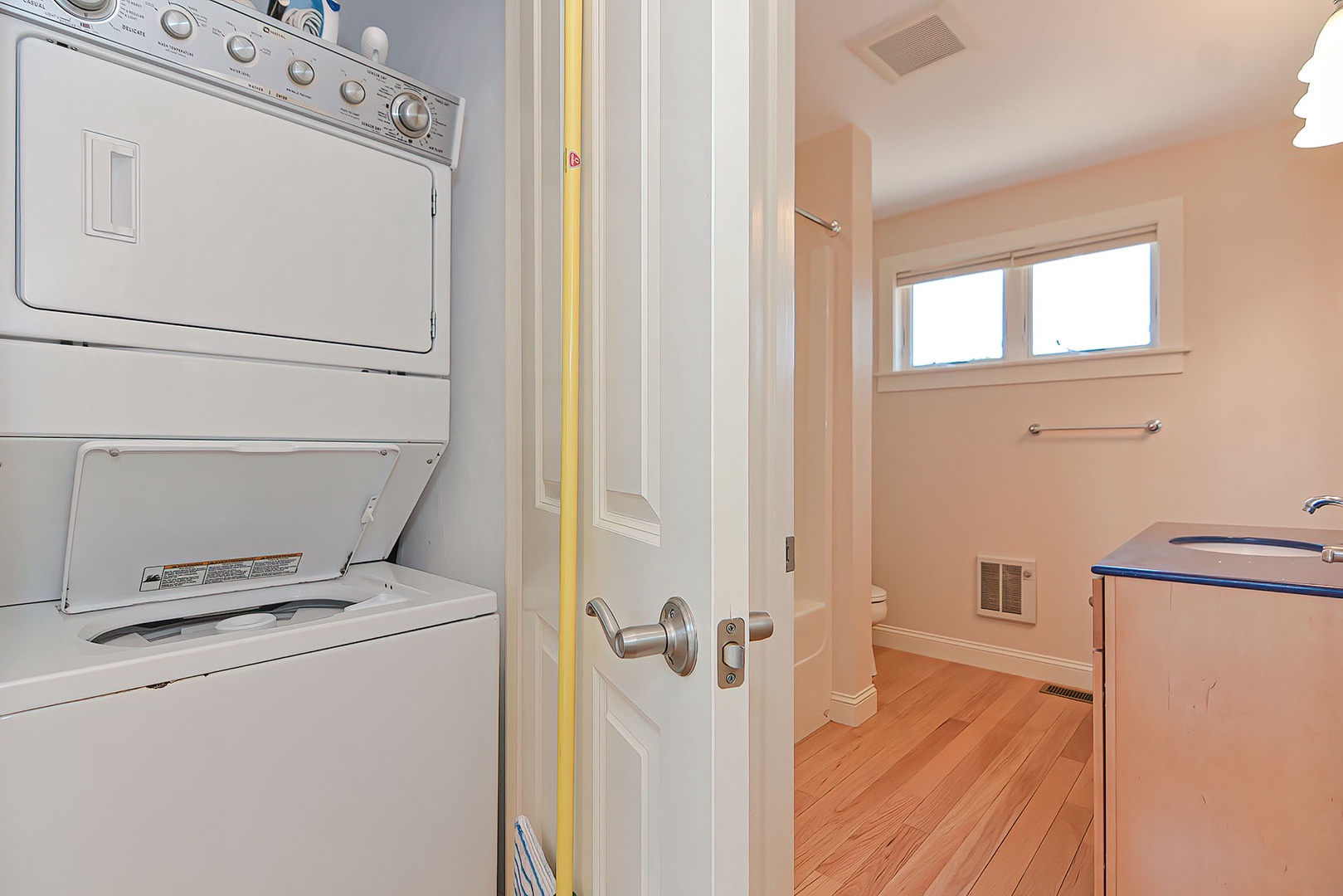 A stacked washer/dryer is tucked into a closet, next to the bath.