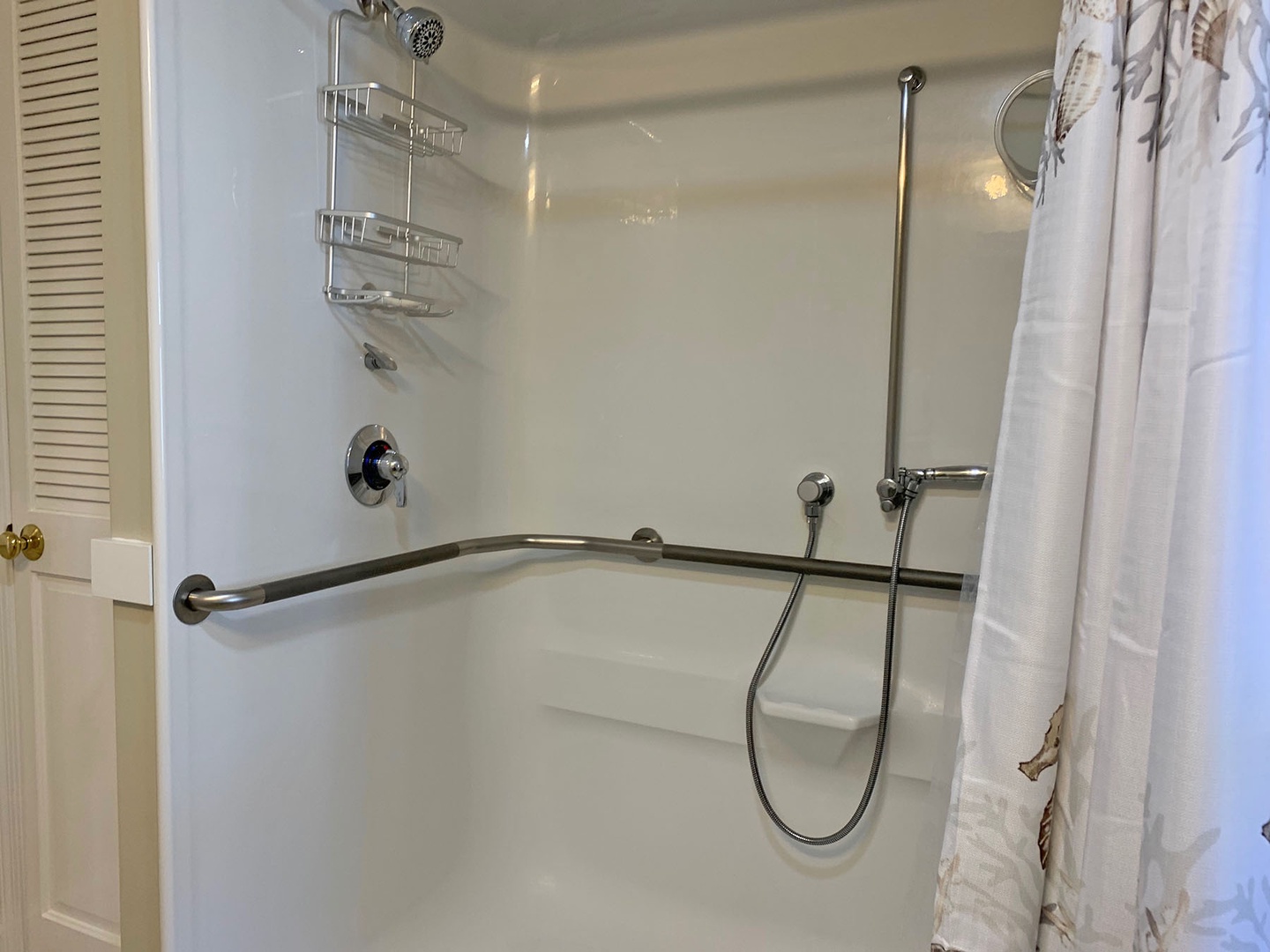The large walk-in shower has grab bars and a seat for accessibility.
