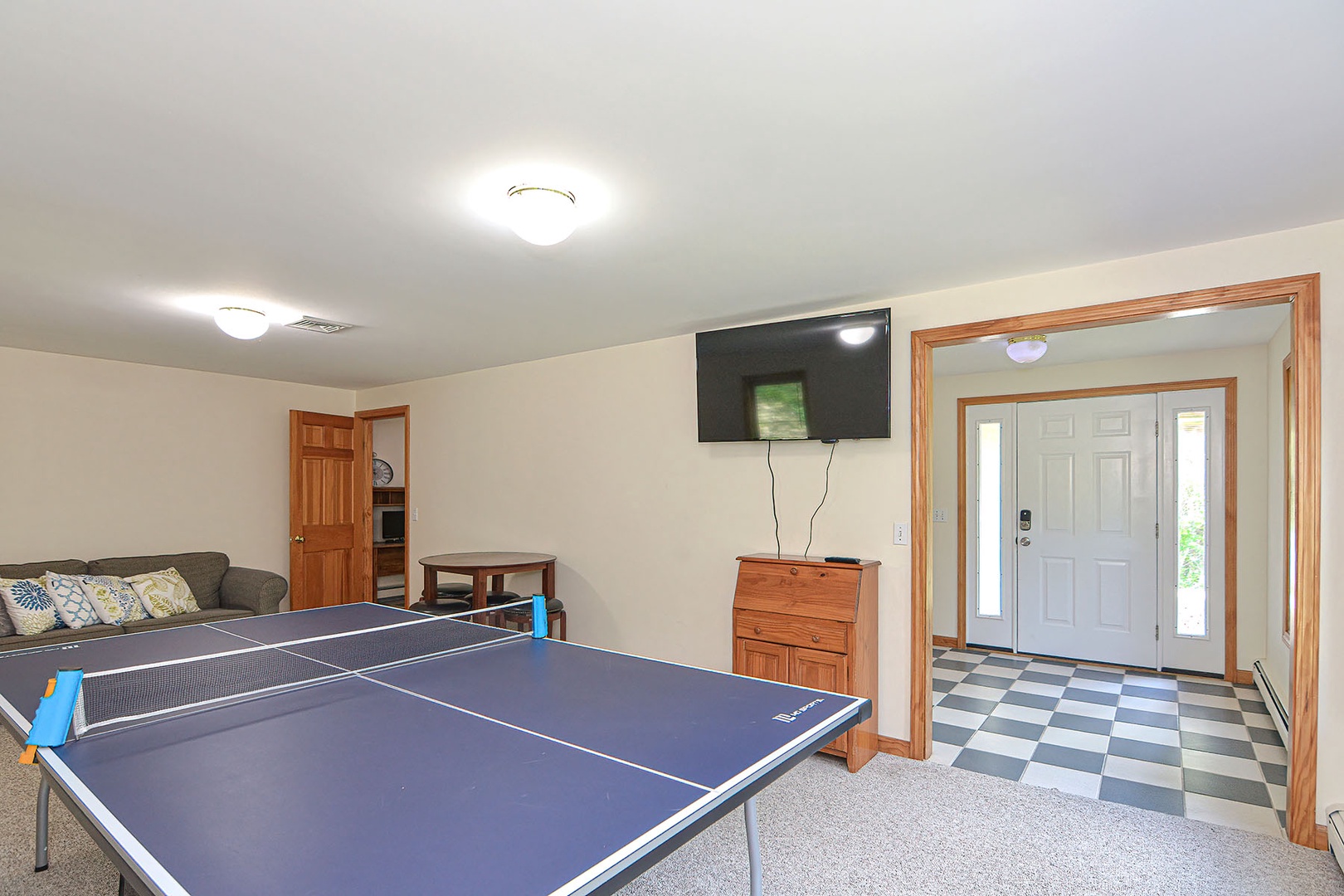 This room has a wall-mounted flatscreen and ping pong table.