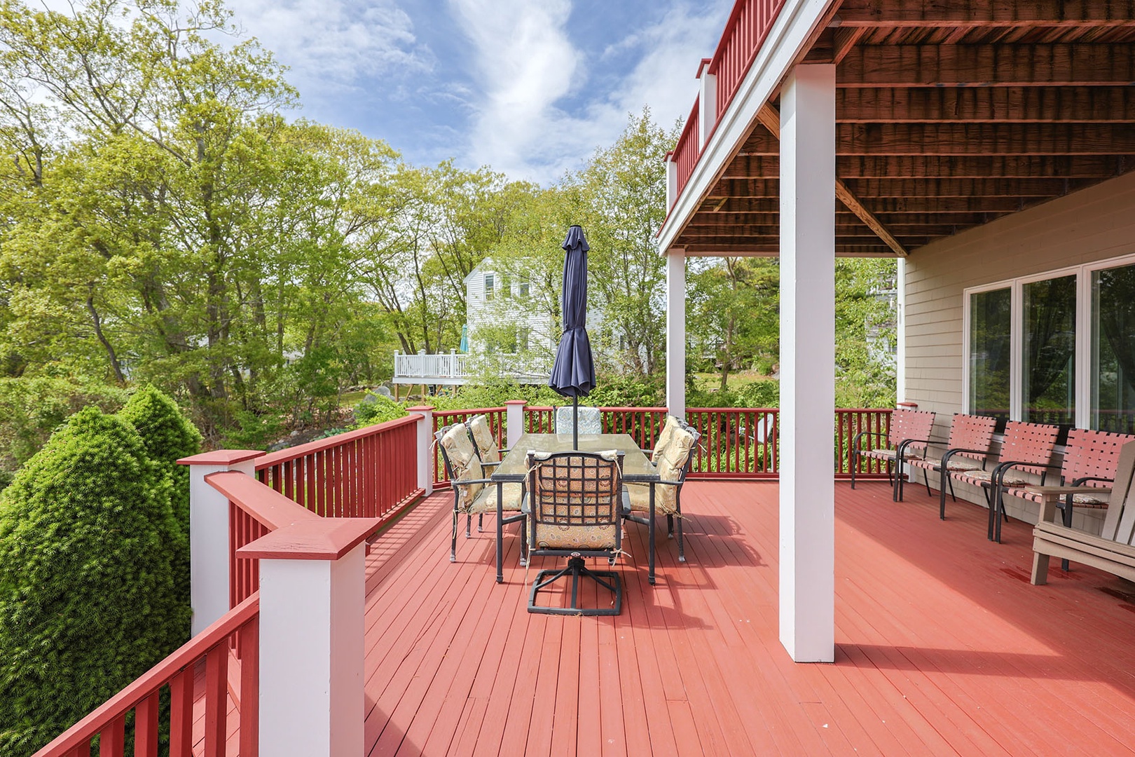 Front deck, surrounded by lush greenery, includes an outdoor dining area