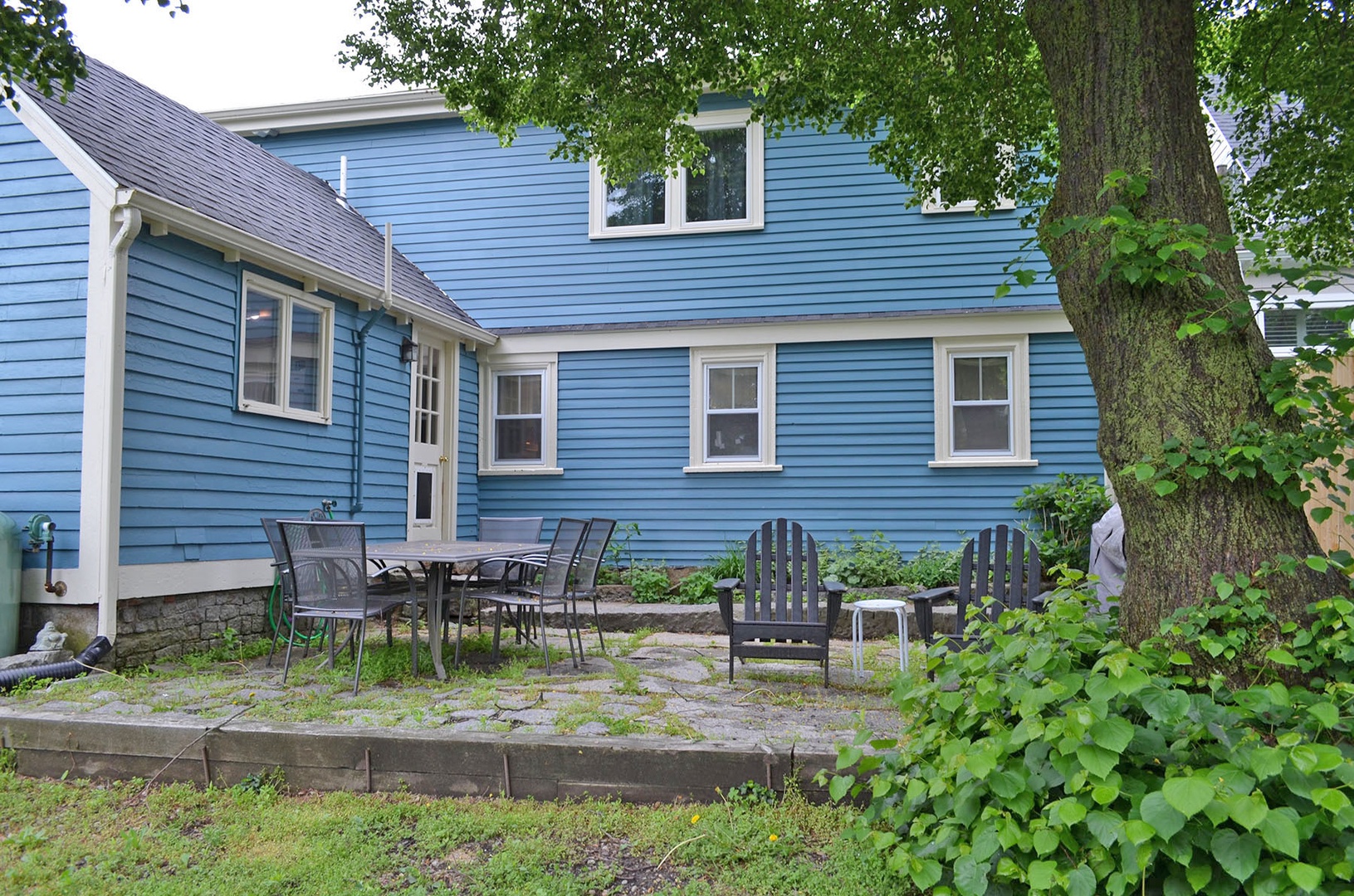 The backyard has a stone patio and dining and sitting areas.