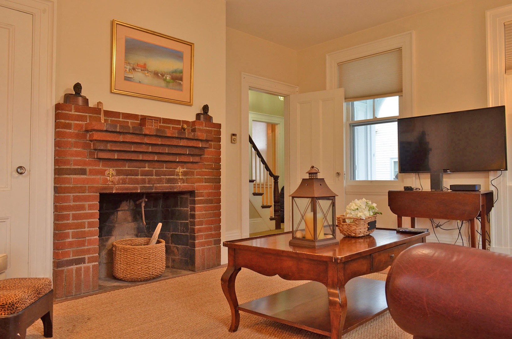 Living room with a large flatscreen TV and original fireplace.