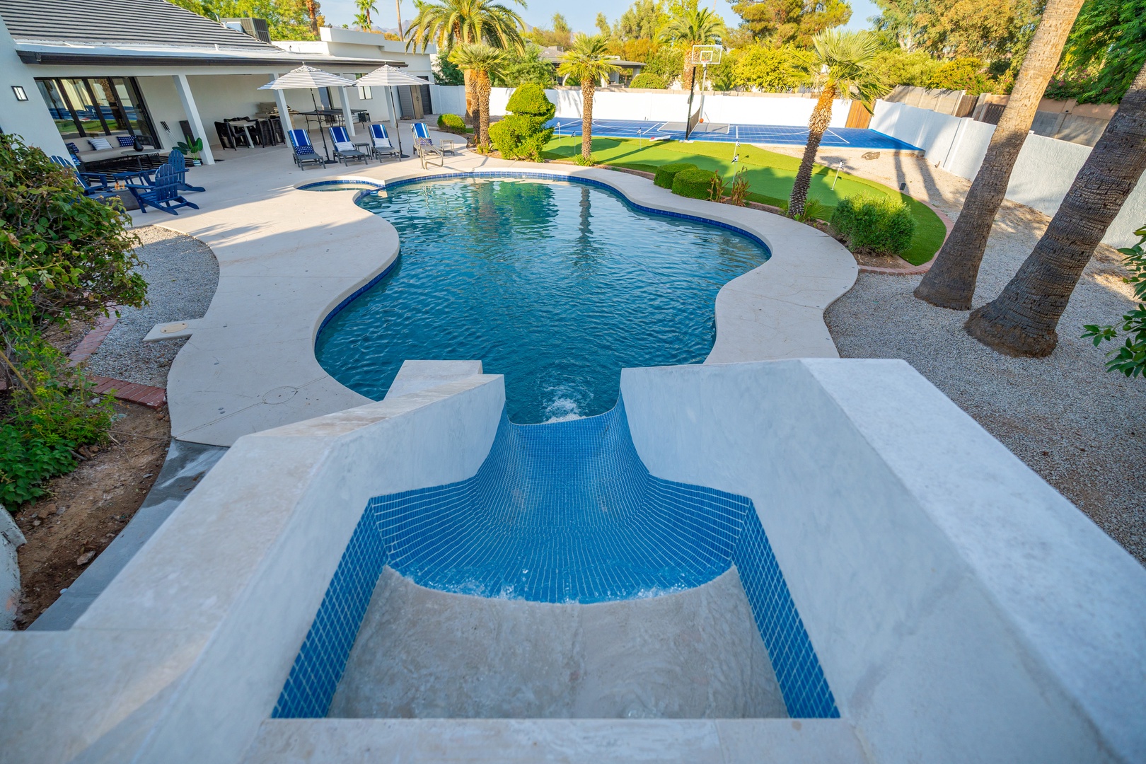 Your private oasis awaits with a sparkling pool, spa, and lush lawn framed by swaying palms—perfect for sunny days and total relaxation.