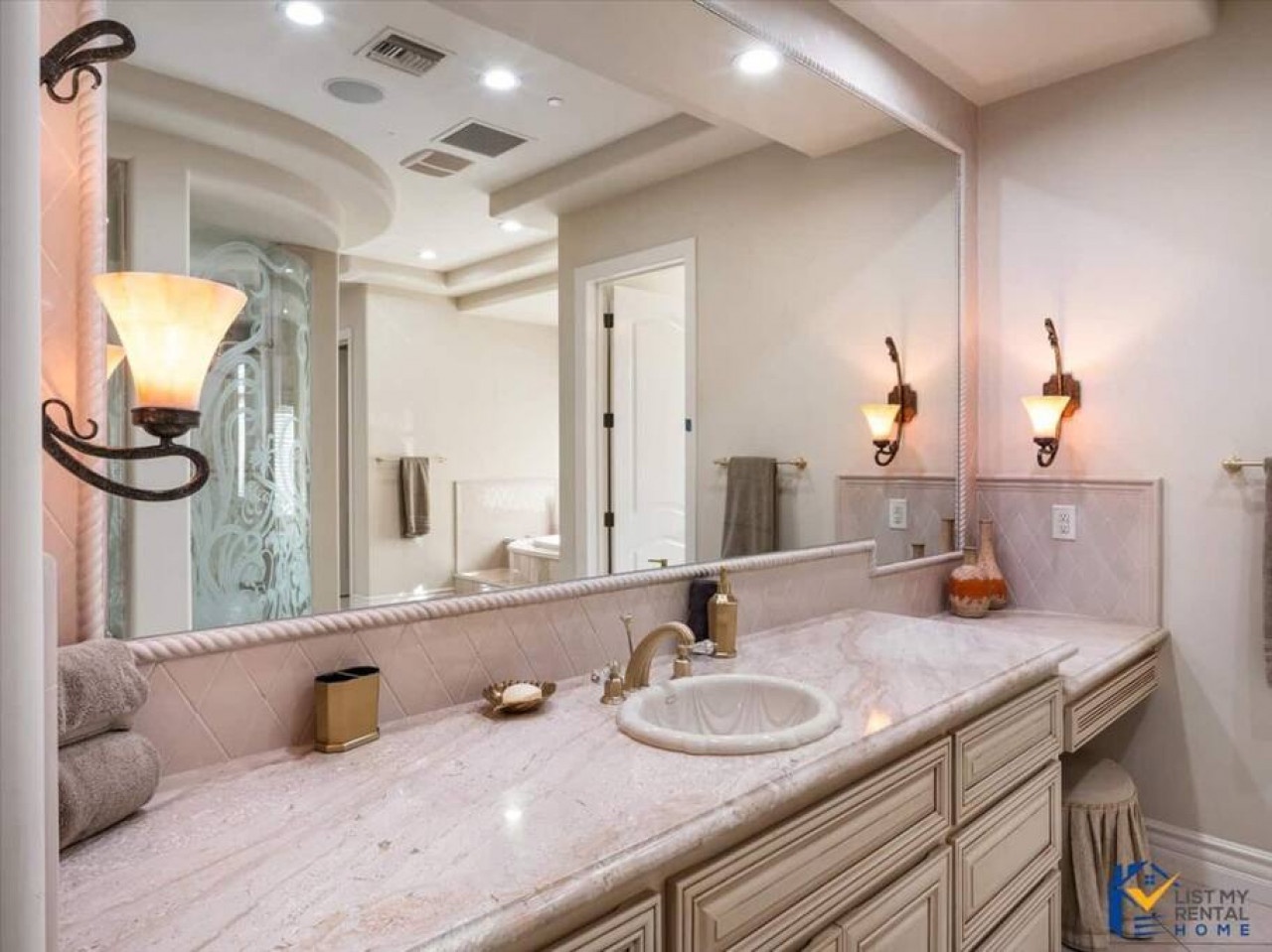 Unwind in your elegant master bathroom featuring marble countertops, warm lighting, and a luxurious glass-enclosed shower for ultimate relaxation.