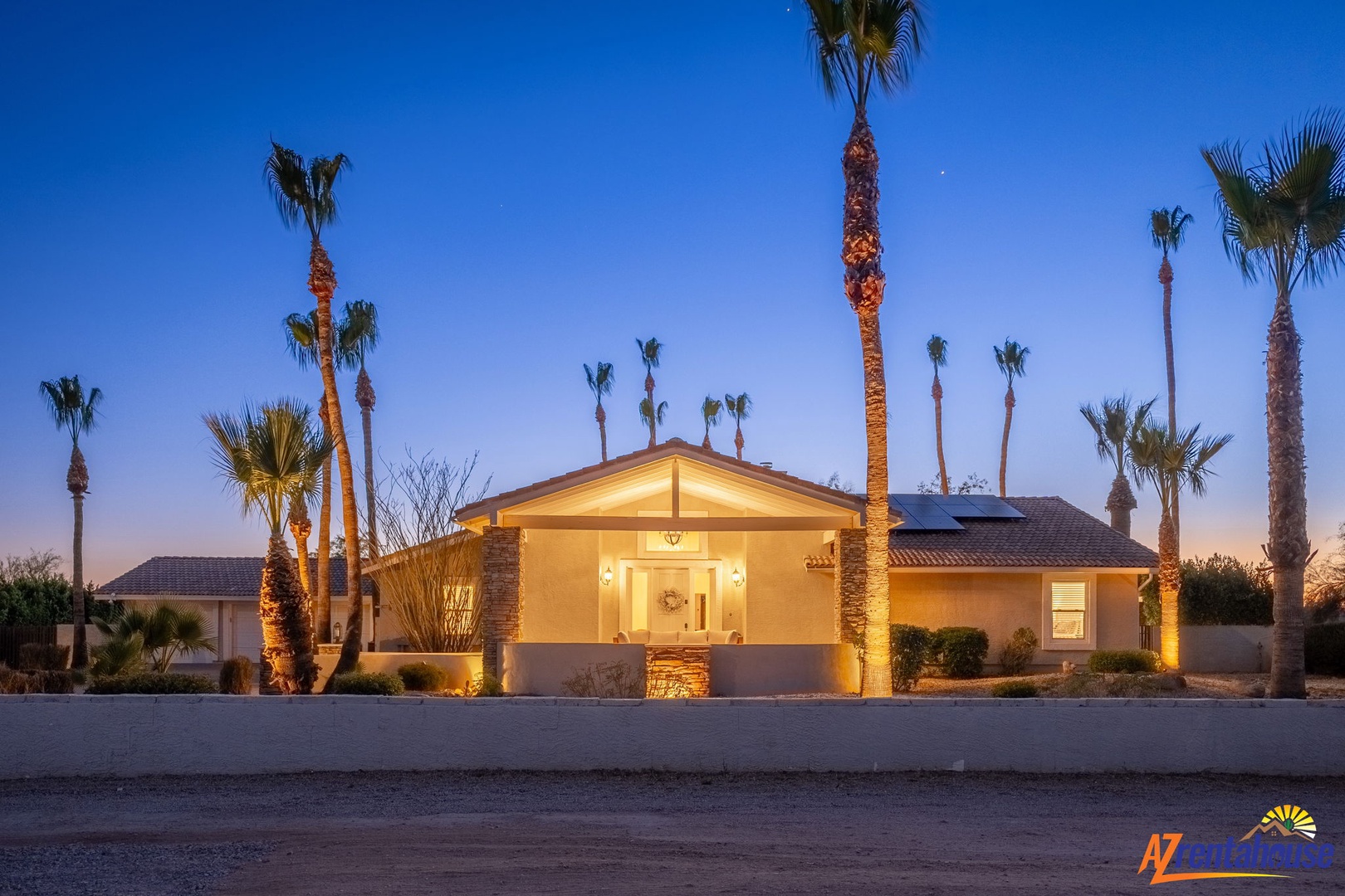 Welcoming desert retreat illuminated under twilight skies, framed by stately palms. This single-story home offers southwestern charm with attached garage, landscaped grounds, and warm evening lighting.