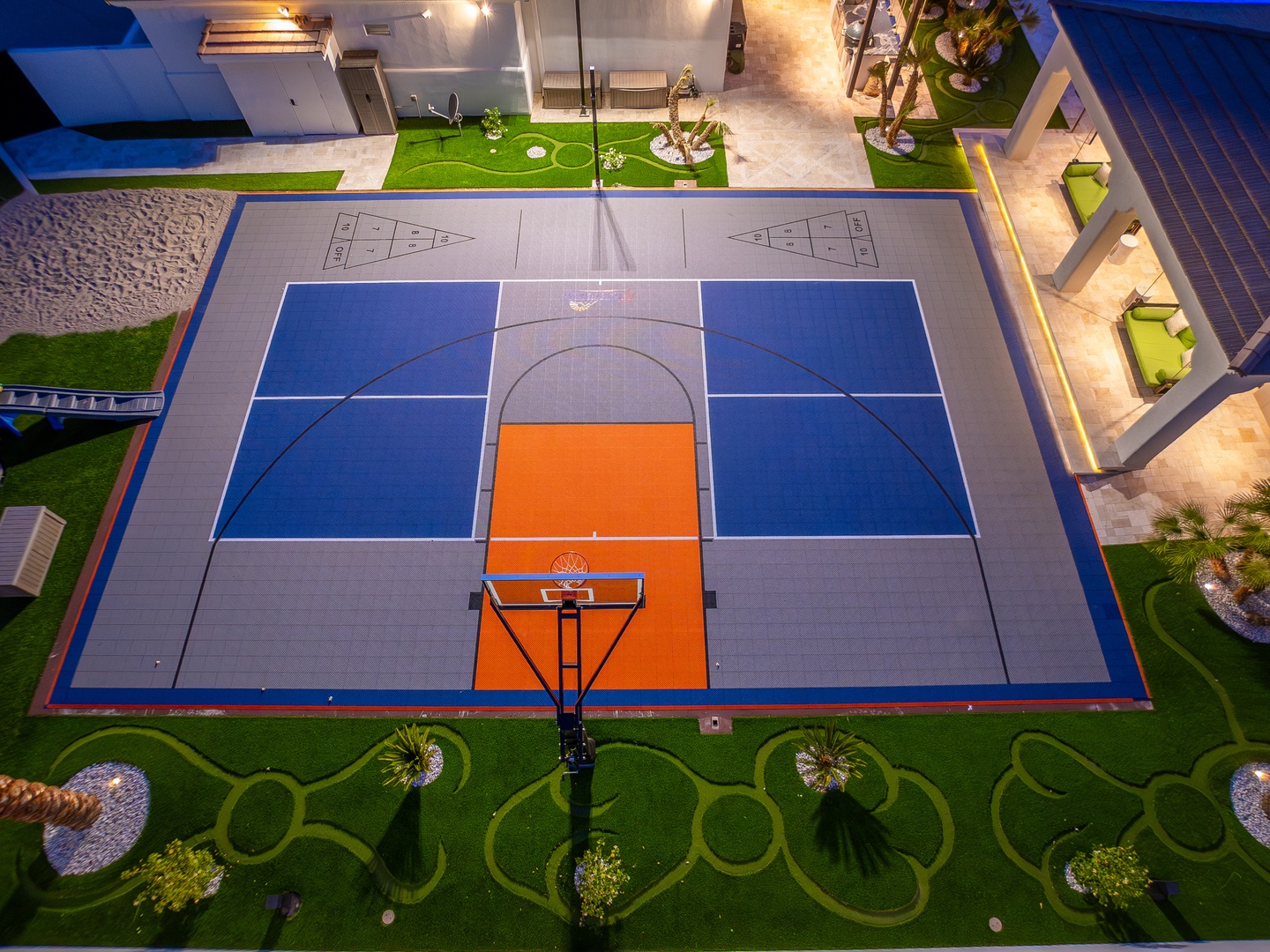 Aerial view of the property's full-sized sports court, landscaped grounds, and poolside lounge areas, perfect for active guests and outdoor gatherings.