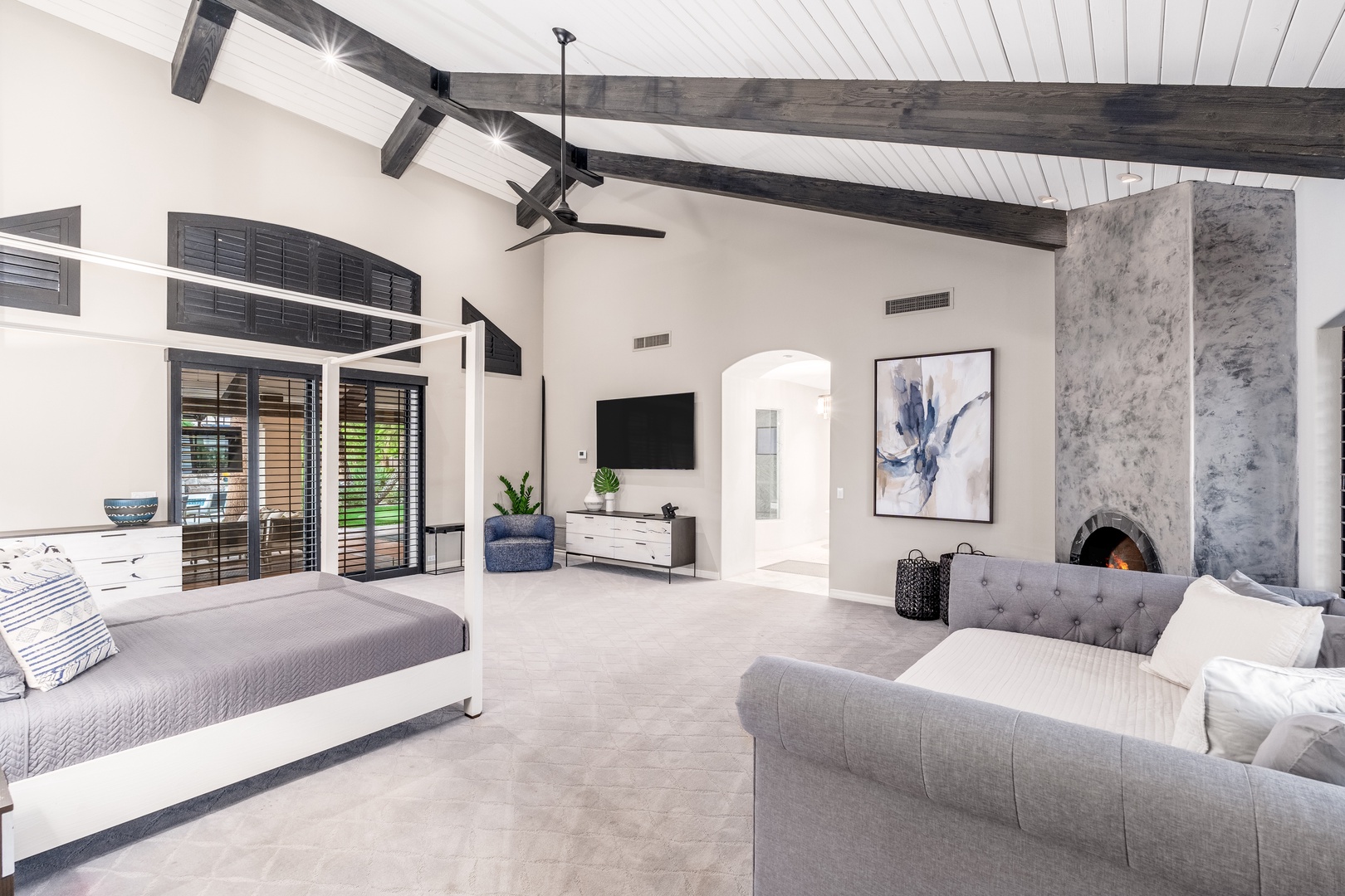 Sink into this spacious suite where vaulted beamed ceilings soar above your plush bed and cozy seating. A cozy fireplace adds warmth while modern touches and natural light create your perfect retreat.