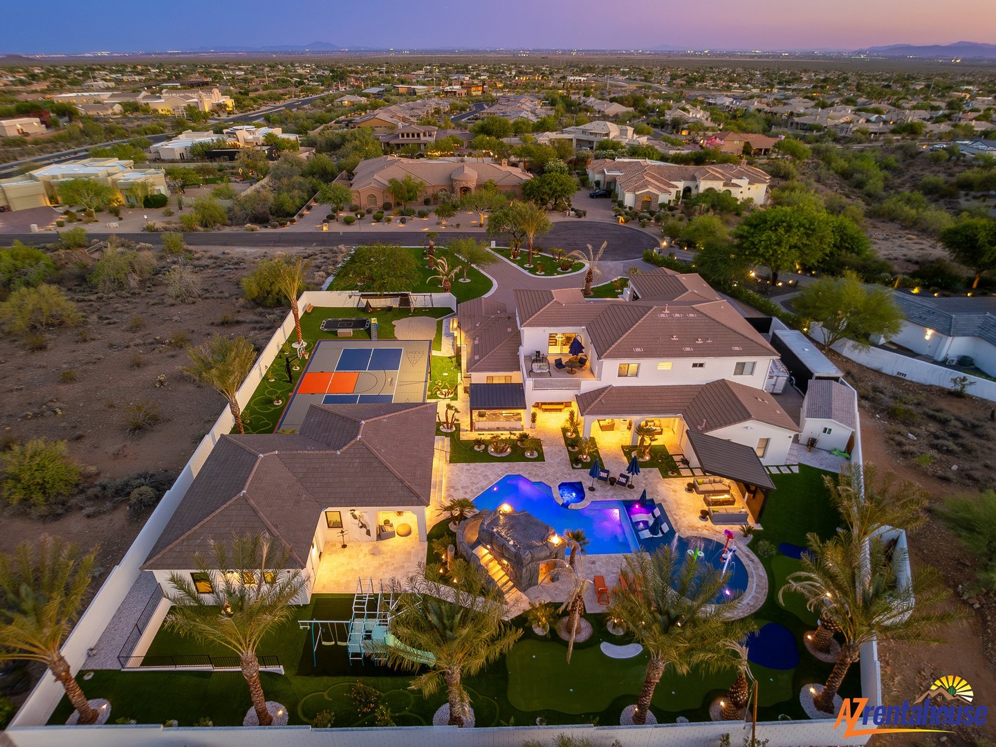 Aerial view of luxury desert estate showcasing sprawling architecture, resort-style pool, and manicured grounds in exclusive residential area.