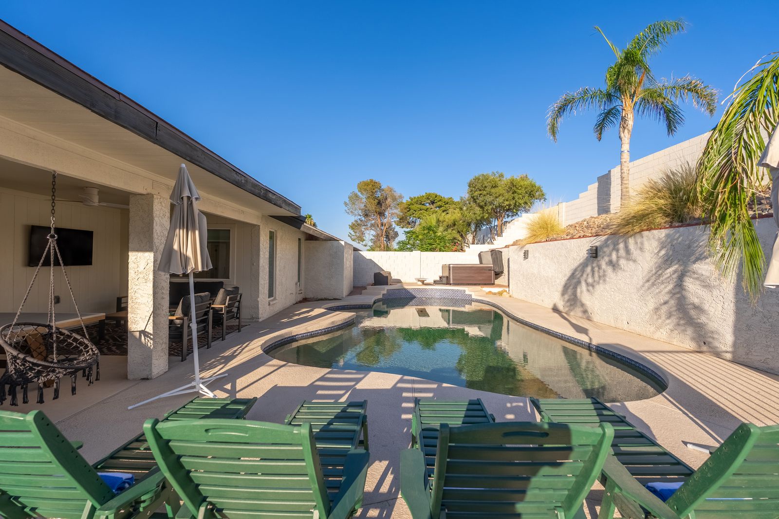 This private backyard oasis features a refreshing pool surrounded by lush palm trees and comfortable loungers—perfect for soaking up the sun or enjoying cool evening swims.