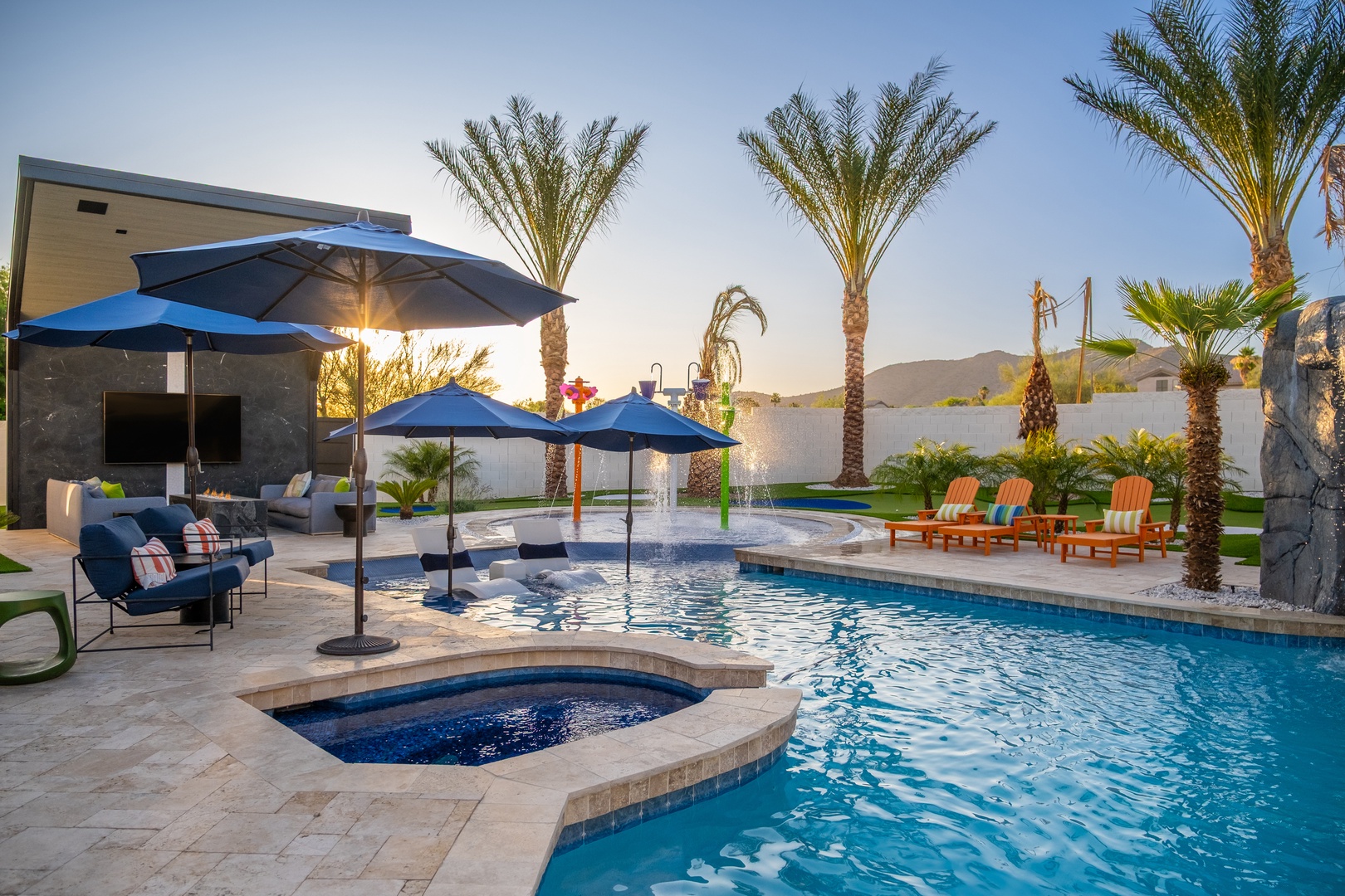 Dive into your private oasis with a sparkling pool, bubbling hot tub, and shaded lounging areas. Palm trees frame mountain views as you relax poolside at sunset.