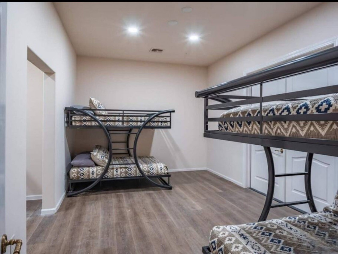 Gather your group in this spacious bunk room with stylish patterned linens and warm wood-look floors, designed to comfortably sleep everyone together after a day of adventure.