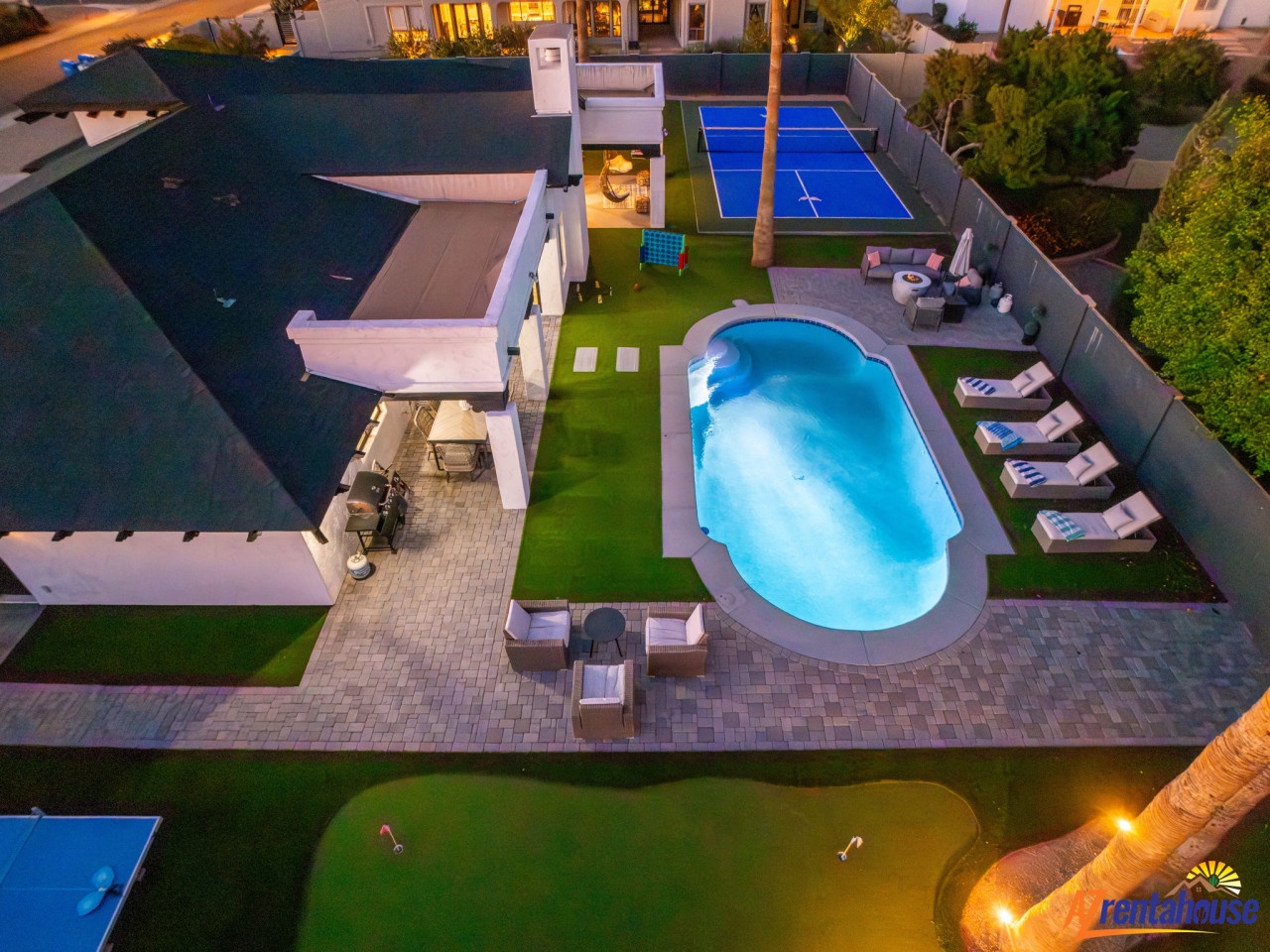 Aerial view of a luxury villa featuring swimming pool, tennis court, and landscaped gardens with outdoor dining areas.