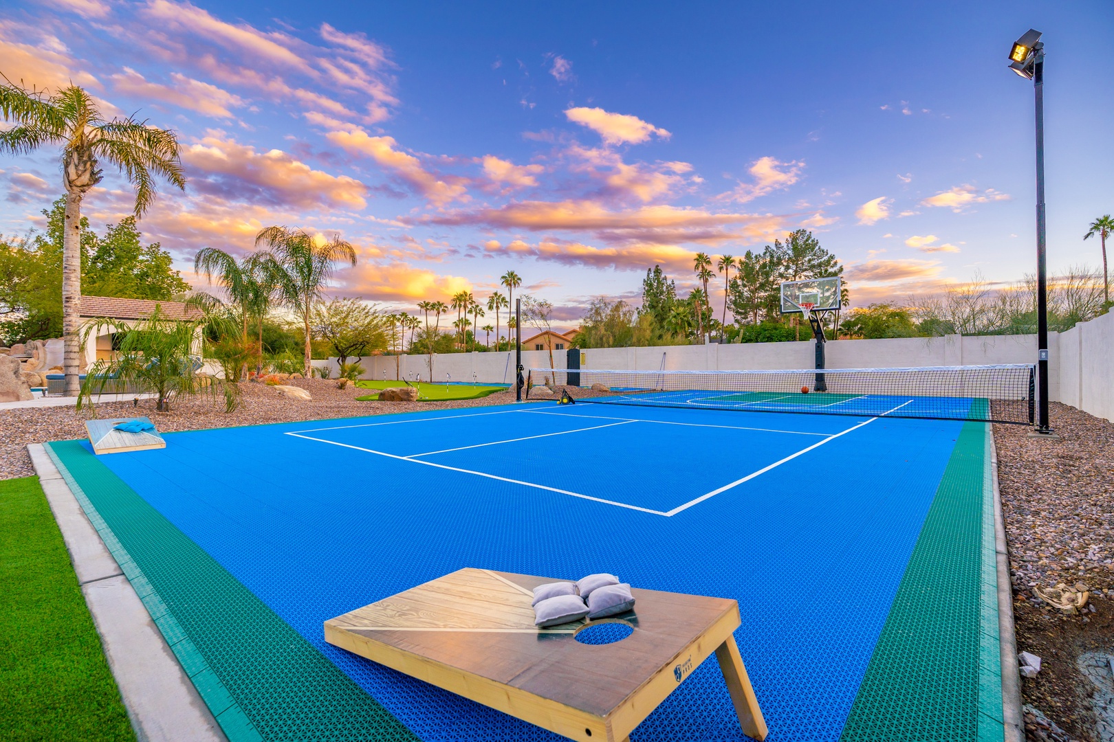 Private tennis court beneath desert palms and vibrant sunset skies—perfect for an evening match or morning rally in this resort-style setting.