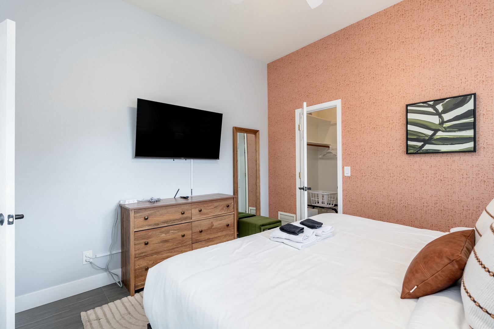 Slip into crisp white linens in your bedroom, where a warm terracotta accent wall and modern art create a soothing retreat. Fresh towels await, and your private ensuite is just steps away.