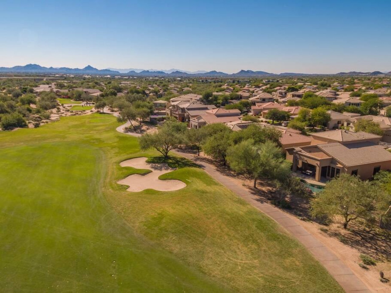 Aerial view showcasing the golf course community with mountain backdrop and desert landscaping throughout the residential area.