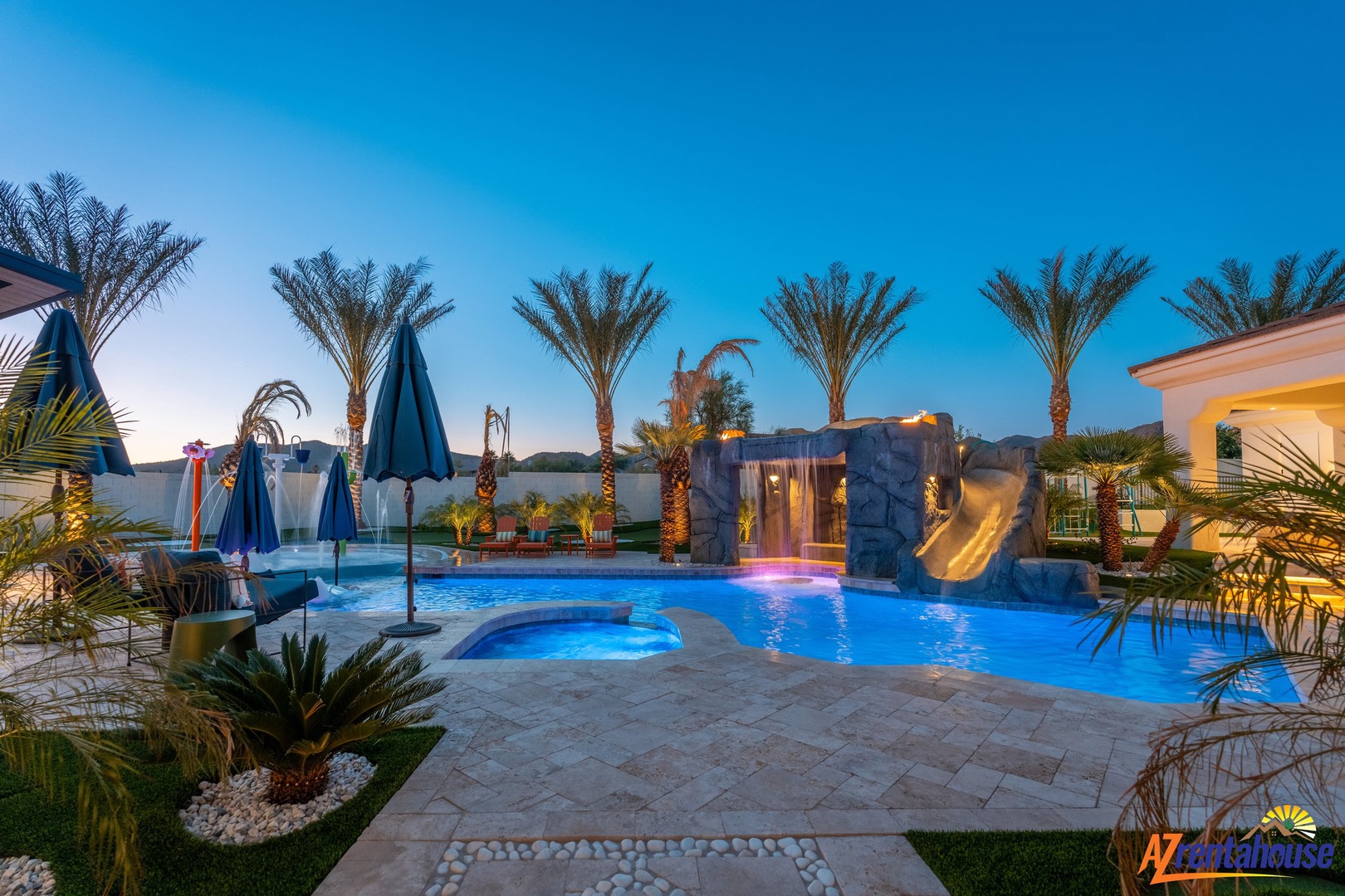 Resort-style pool area with waterslide, hot tub, and tropical palm landscaping creates a luxurious outdoor retreat.