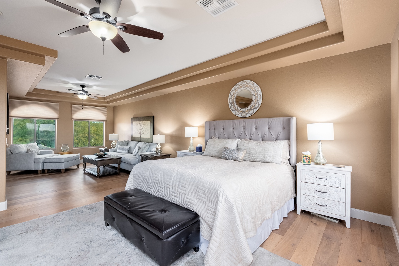 Unwind in your spacious master suite featuring a plush king bed, elegant tufted headboard, and relaxing seating area—your private retreat after adventurous days exploring the area.