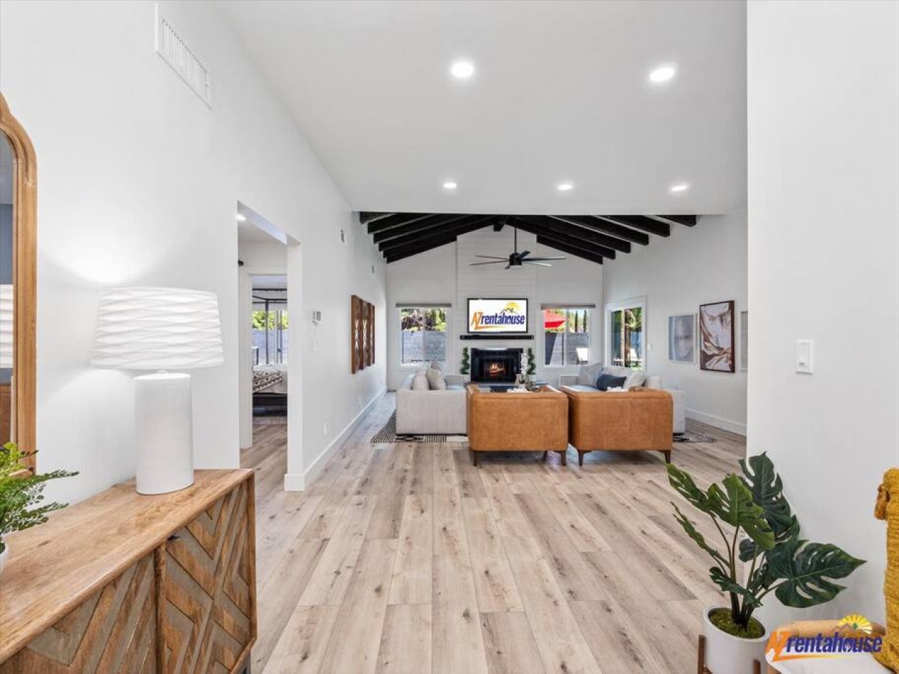 Unwind in this stunning open-concept living space with soaring beamed ceilings, cozy fireplace, and elegant furnishings that invite relaxation.