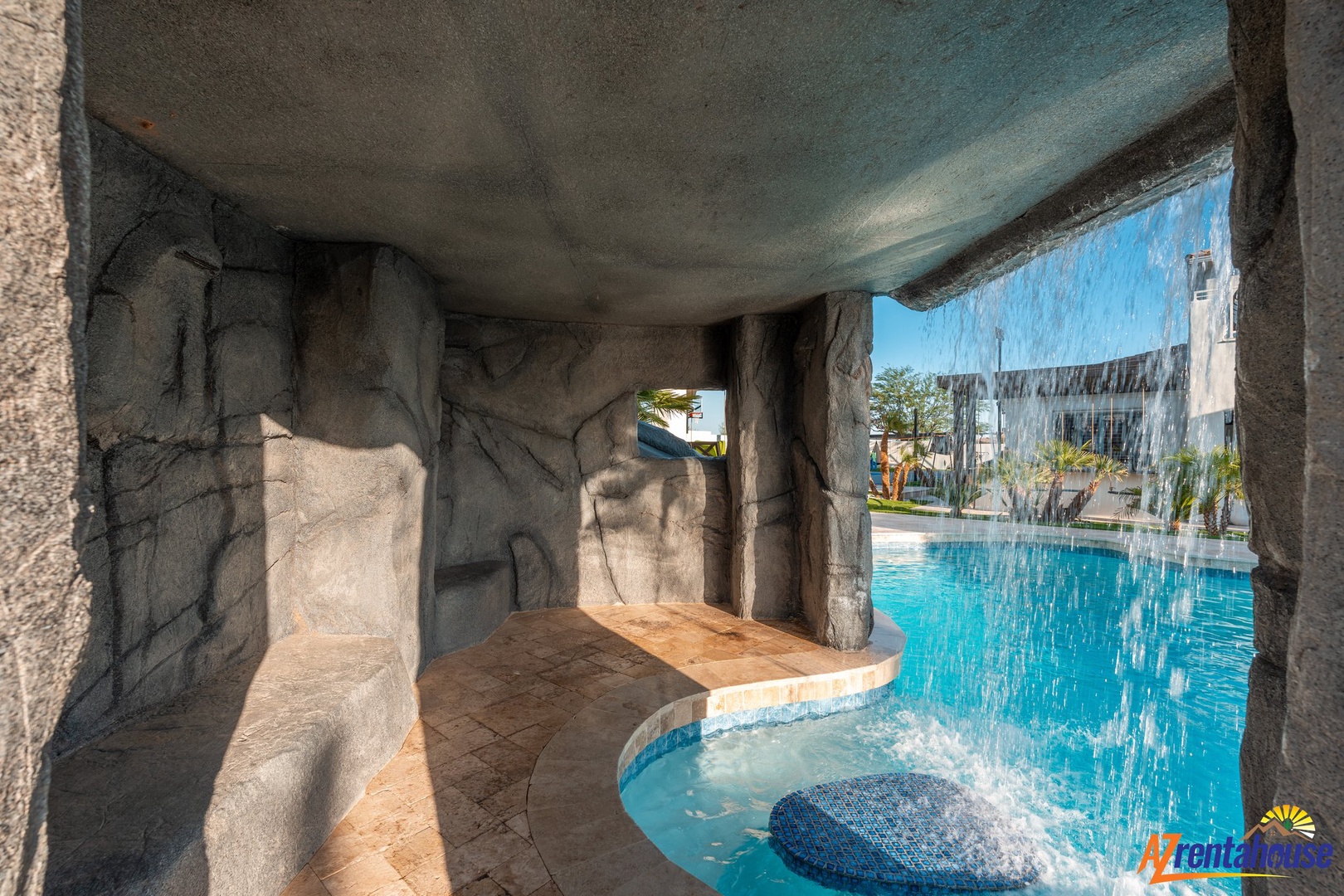 Step into your own private grotto where cascading waterfalls create a tranquil sanctuary beside the sparkling pool.