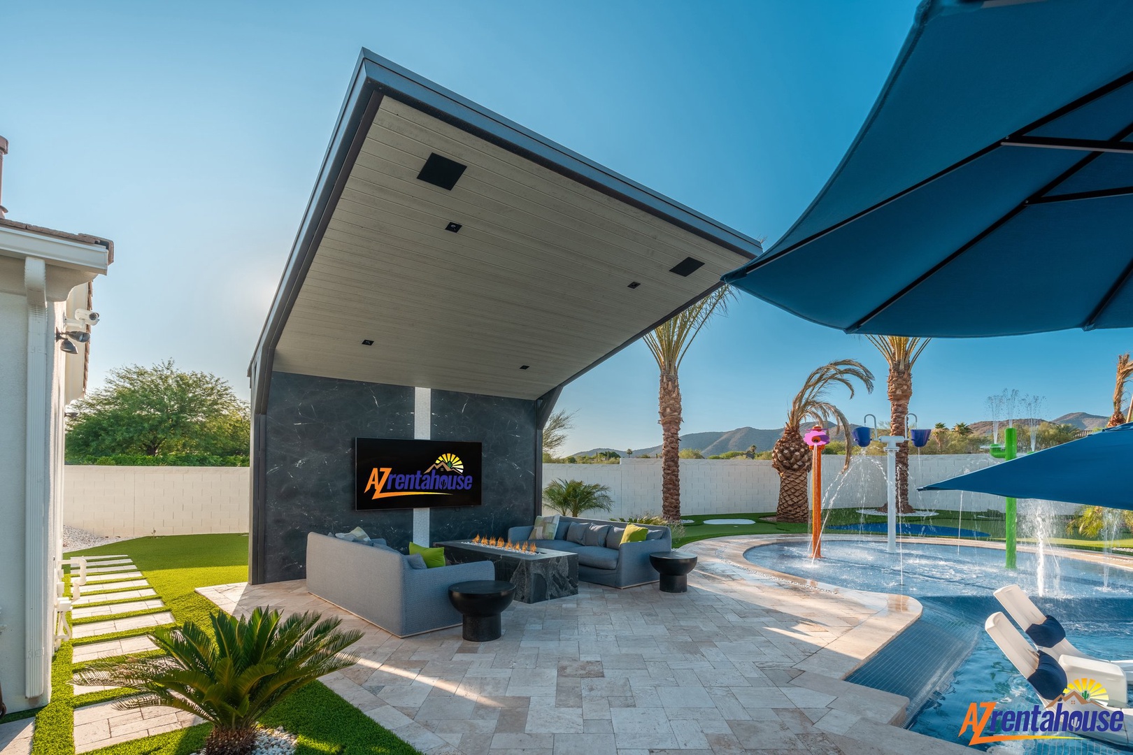 Relax in your private outdoor oasis featuring a sparkling pool, covered lounging area with modern fireplace, and lush desert landscaping.