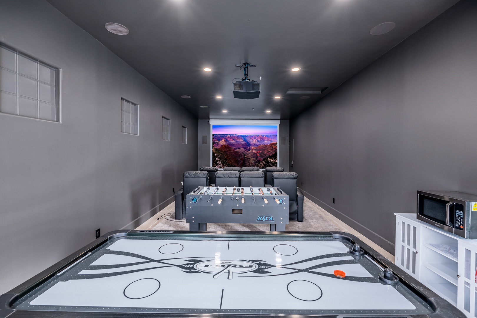 Your ultimate entertainment space features air hockey, foosball, cozy theater seating, and a projector for epic movie nights—perfect for fun-filled evenings with family and friends.