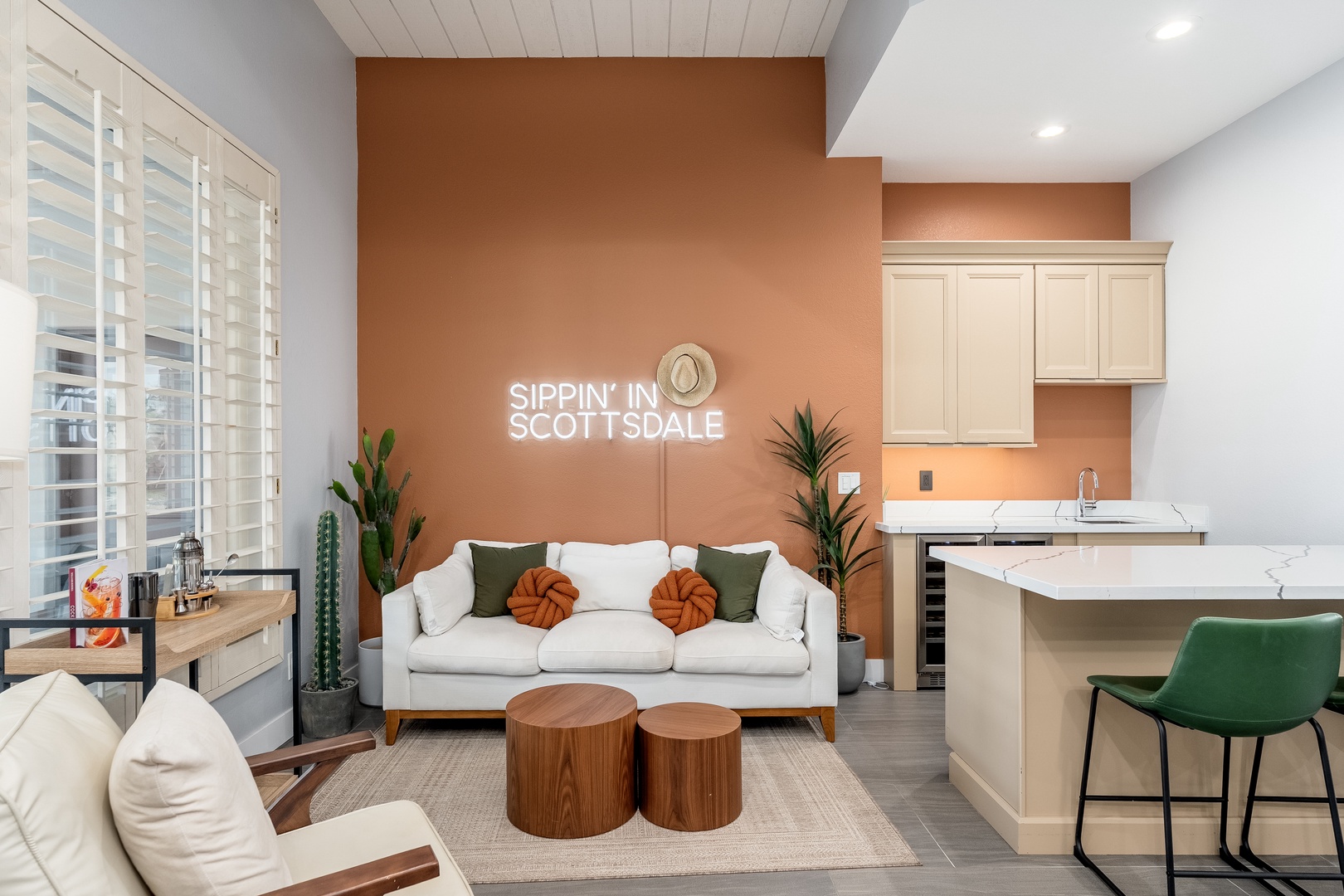 Settle into your inviting open-concept living area with a chic white sofa, modern accents, and a sleek kitchenette—perfect for sipping coffee and soaking in the warm desert vibes of Scottsdale.