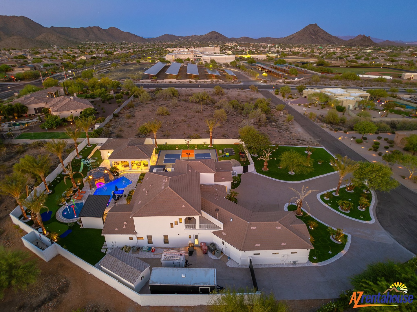 Sprawling desert oasis estate with pools, sports court, and manicured grounds set against Arizona's dramatic mountain landscape.