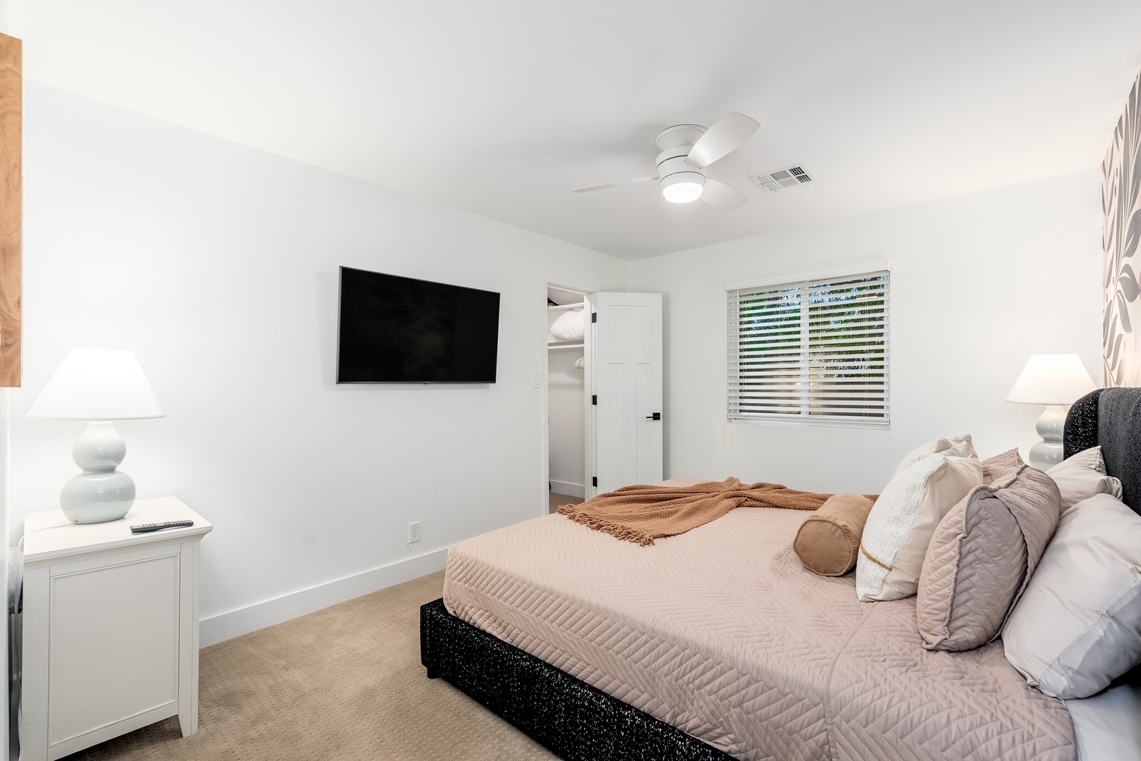 Sink into your plush bed after a day of exploring, with natural light filtering through the blinds and a ceiling fan keeping you cool. Your wall-mounted TV awaits for cozy movie nights in this serene retreat.