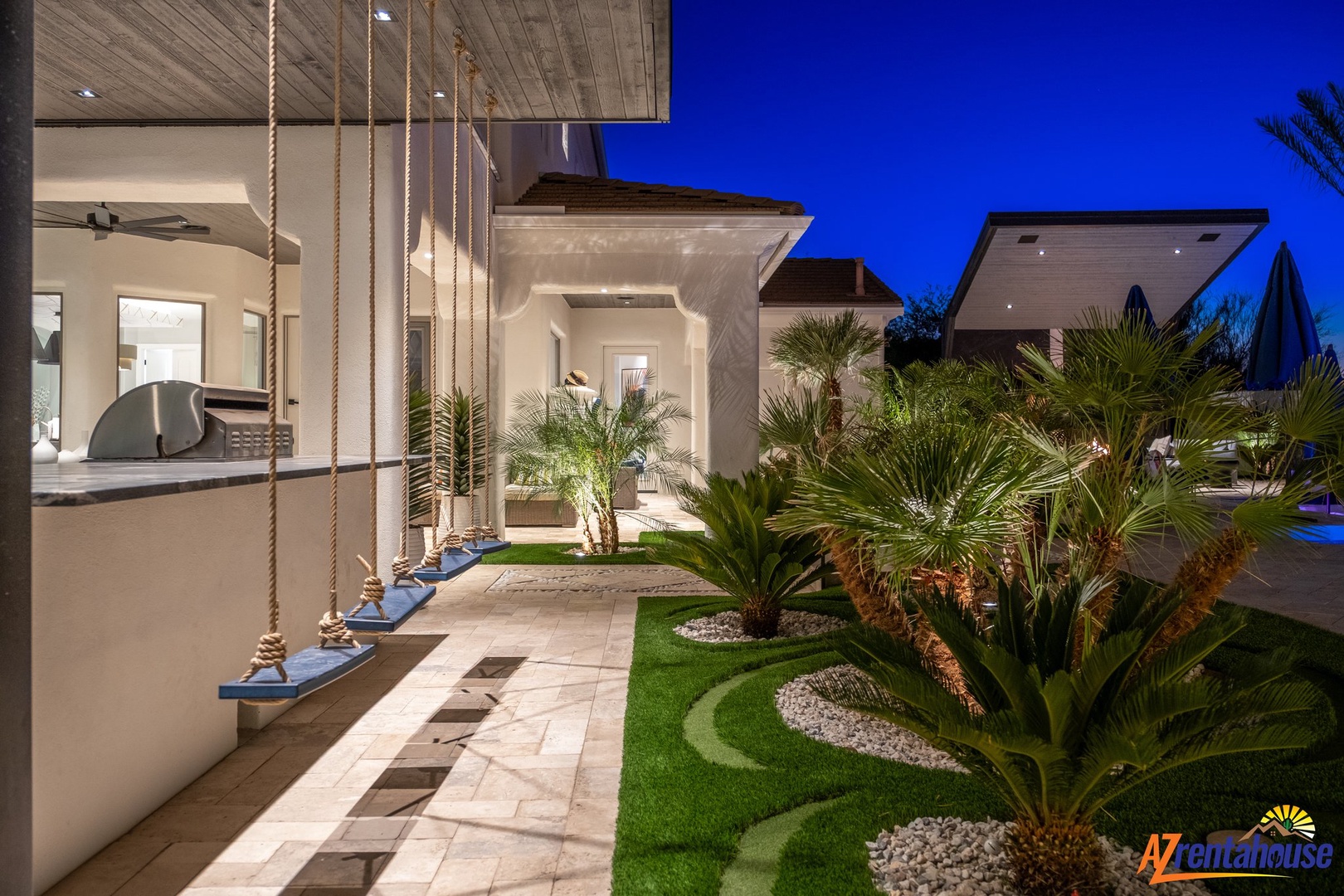 Modern luxury villa with stunning tropical landscaping and contemporary design, perfectly illuminated for an elegant evening atmosphere.