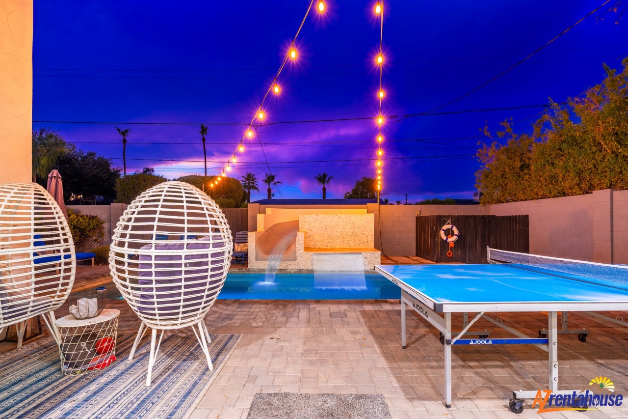 Modern poolside area featuring festive string lighting and recreational amenities for evening entertainment.