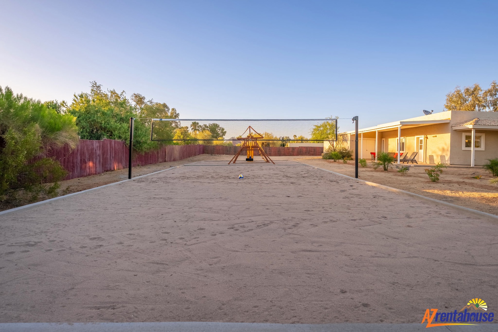 Spacious outdoor court with volleyball net and playground, perfect for friendly games and family fun under the open sky.