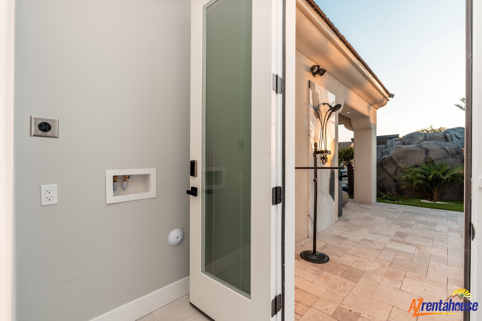 Step through elegant glass doors onto your private covered patio, where warm stone flooring and thoughtful lighting create the perfect evening retreat.