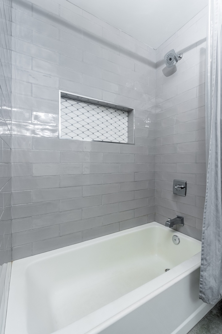 Sink into a soothing soak in your pristine bathtub, surrounded by gleaming white subway tile and modern fixtures that make every moment feel refreshing.