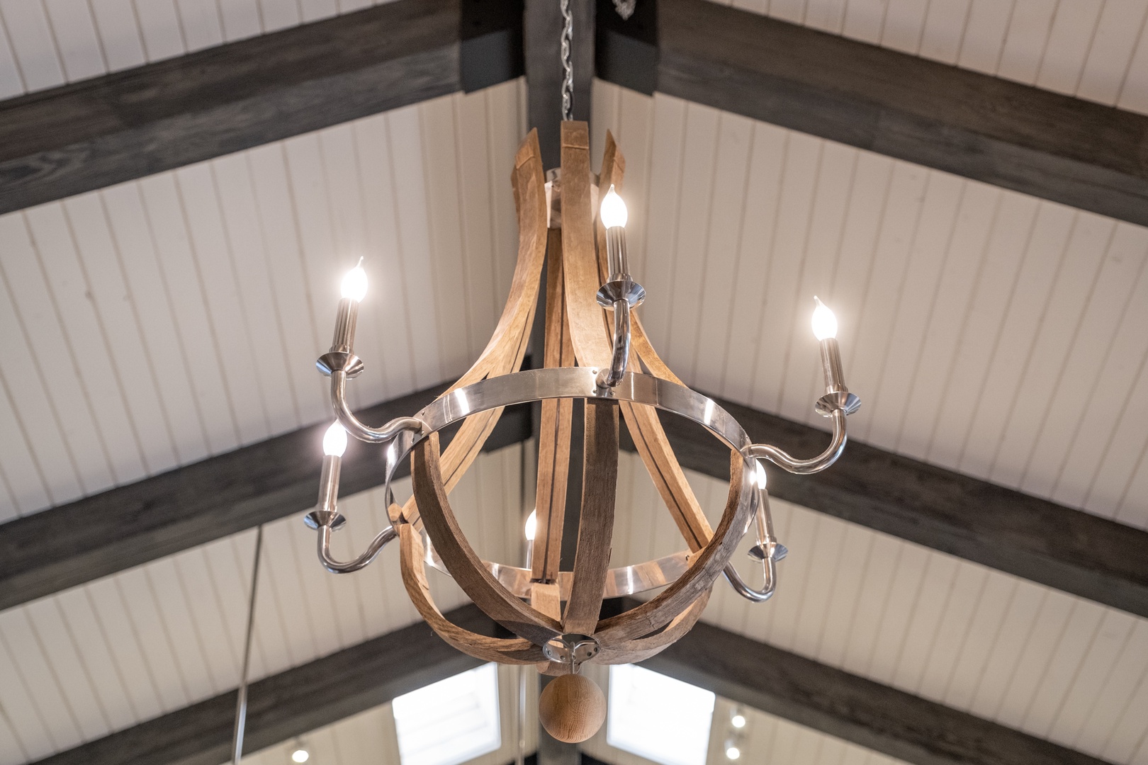 A rustic wood and metal chandelier hangs from soaring vaulted ceilings, adding farmhouse charm and warm ambiance to your retreat space.