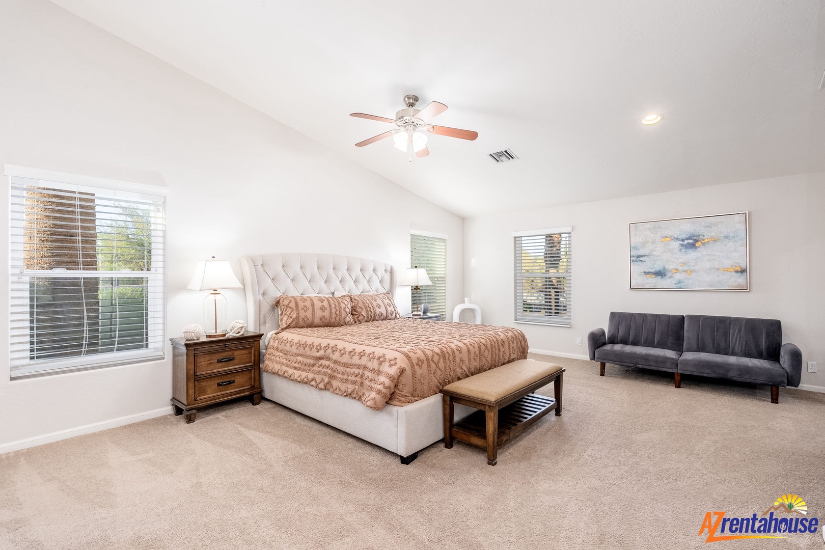 Picture yourself unwinding in this bright, spacious bedroom—your plush king bed awaits, with a ceiling fan overhead and soft carpeting underfoot, creating a peaceful retreat for restful nights.