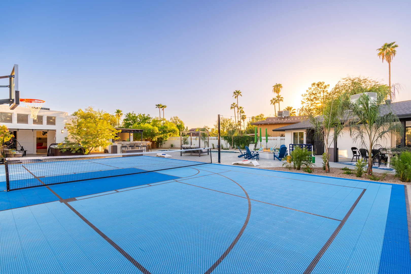 Full-size sport court surrounded by palm trees and modern vacation homes at sunset, ideal for active retreats in a warm desert setting.