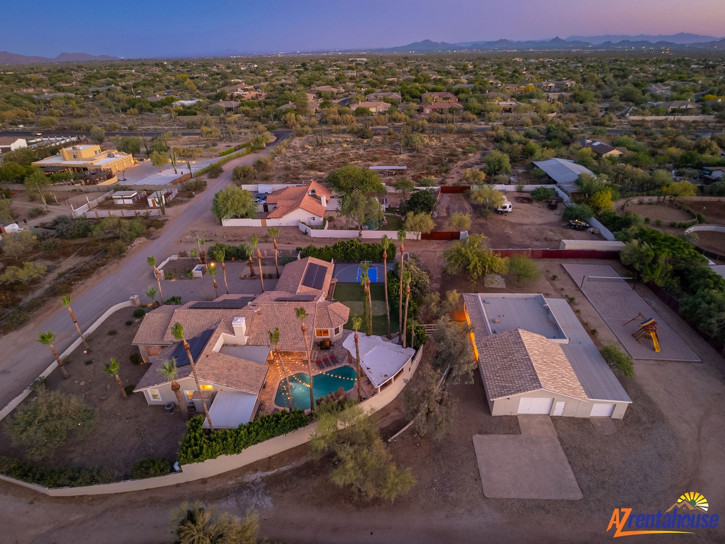Aerial view of a sprawling desert property featuring a spacious pool and surrounded by natural Sonoran landscape with mountain views.