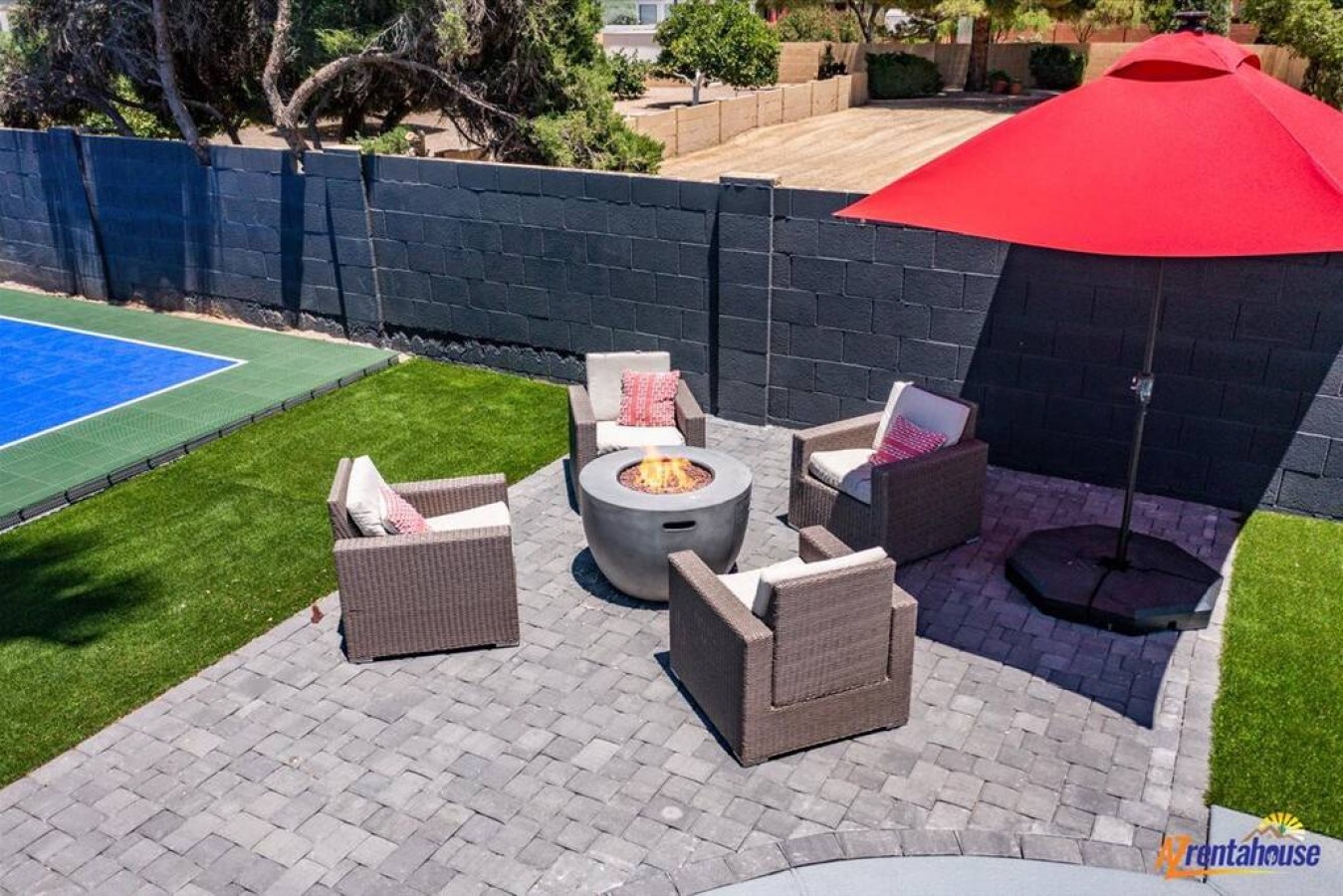 Gather around your private fire pit under the bright red umbrella, creating perfect evening memories on this beautifully landscaped patio.