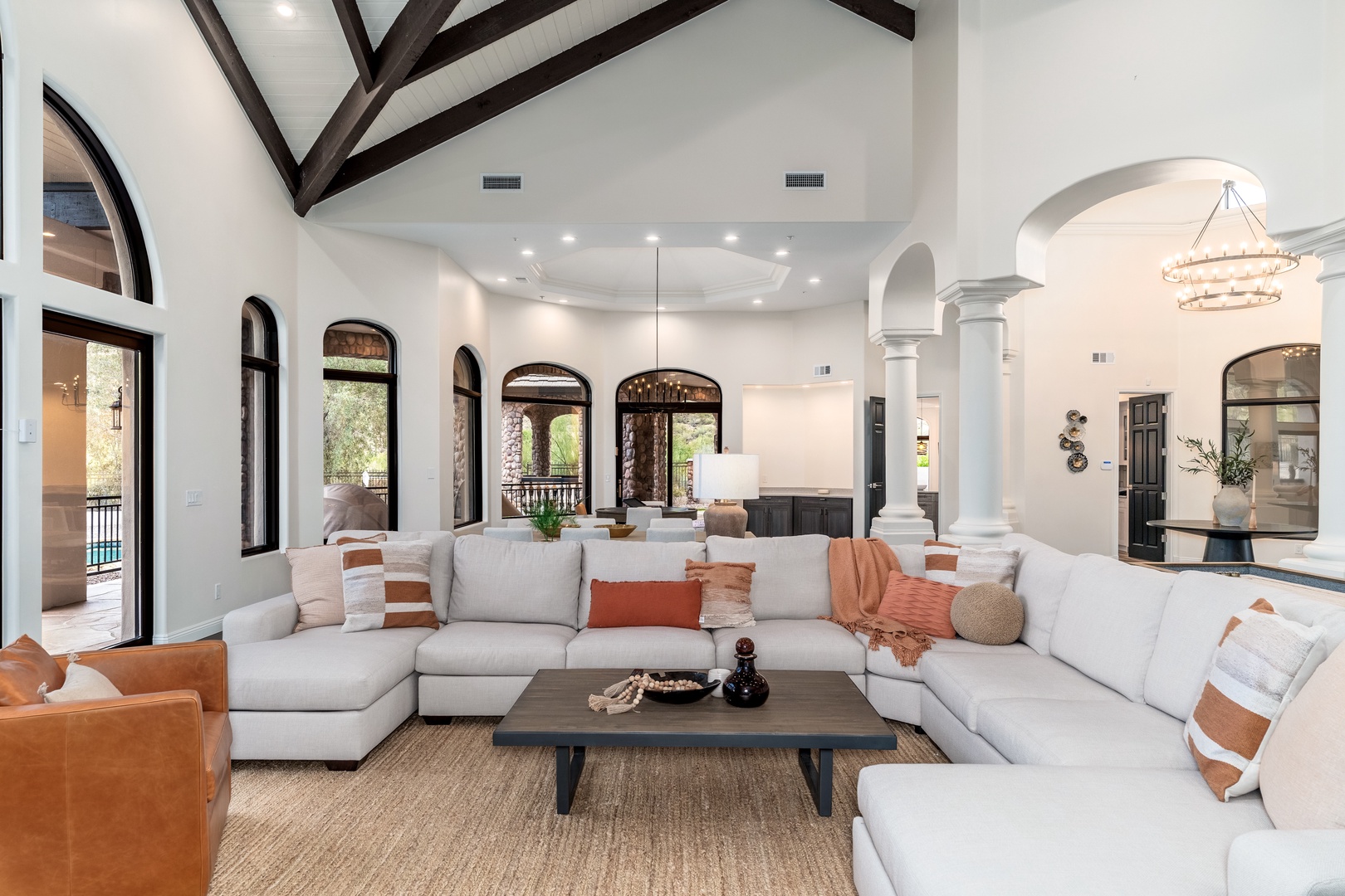 Gather your group in this stunning living space with soaring ceilings, exposed beams, and sunlight streaming through elegant arched windows. Sink into plush seating and feel right at home in this thoughtfully designed retreat.
