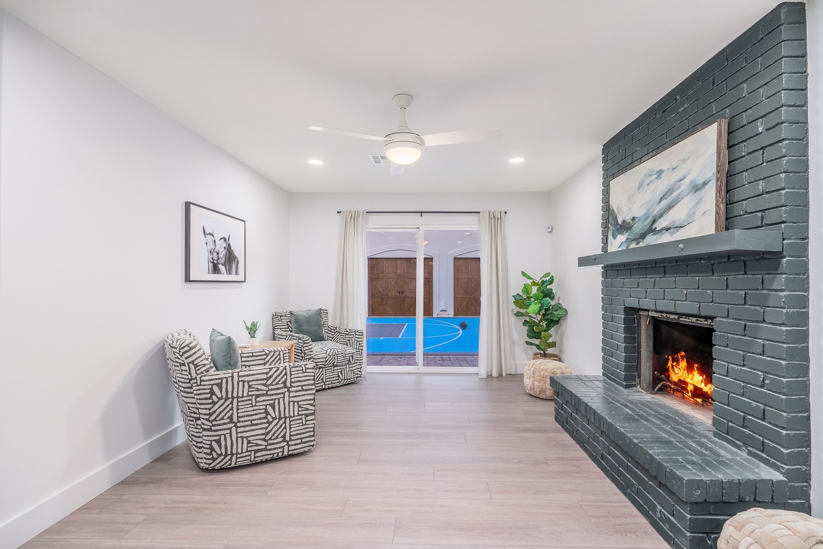 Unwind in your cozy living space, where a striking fireplace sets the mood, modern seating invites relaxation, and sliding doors open to your private pool oasis.