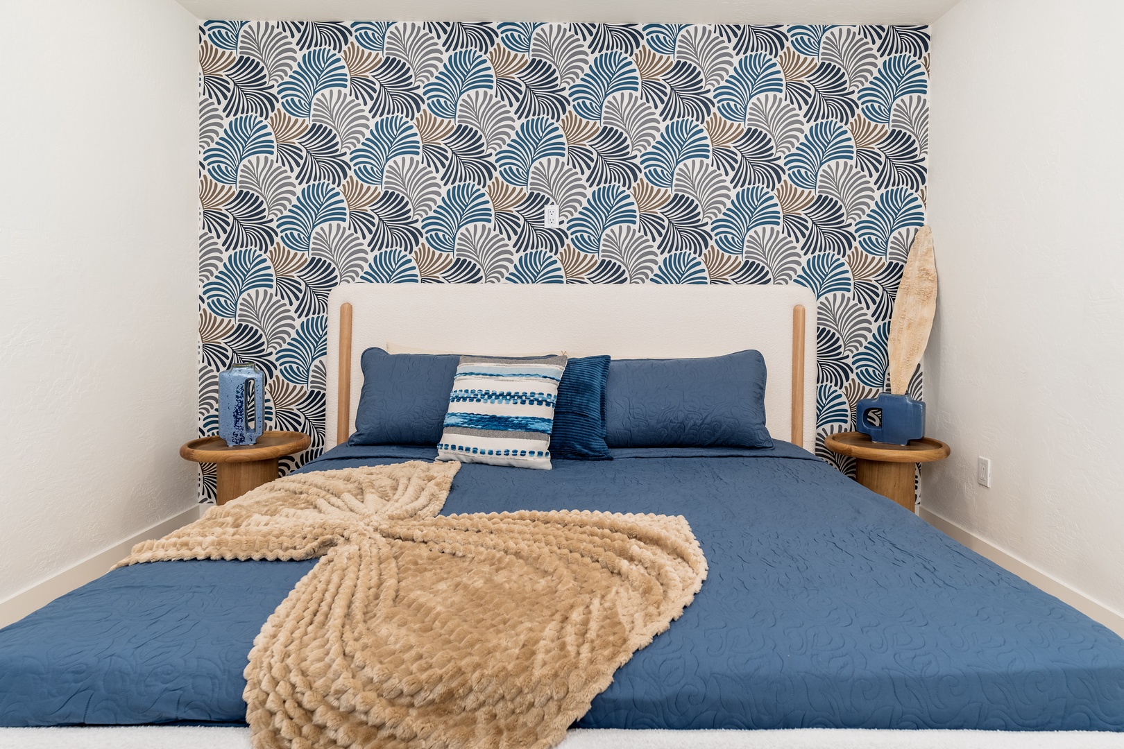 Sink into plush bedding in this coastal-inspired bedroom, where textured details and a striking wave-patterned accent wall create your serene escape by the sea.